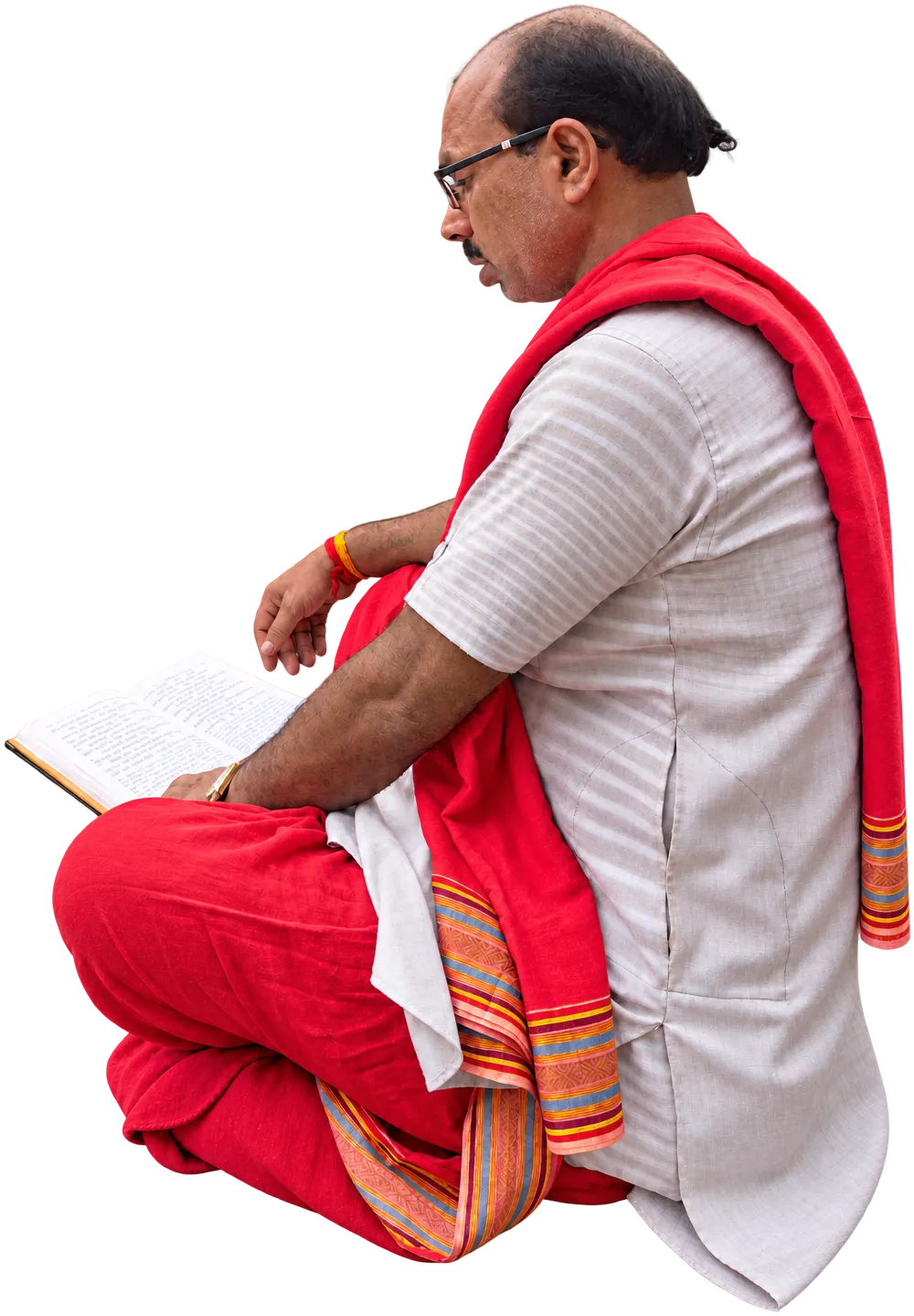 A priest in a red stole, seated cross-legged, reading scripture at the Kamakhya temple