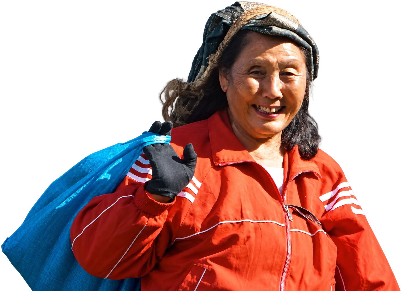 A tea picker in an orange jacket, smiling, a sack over her shoulder, Darjeeling