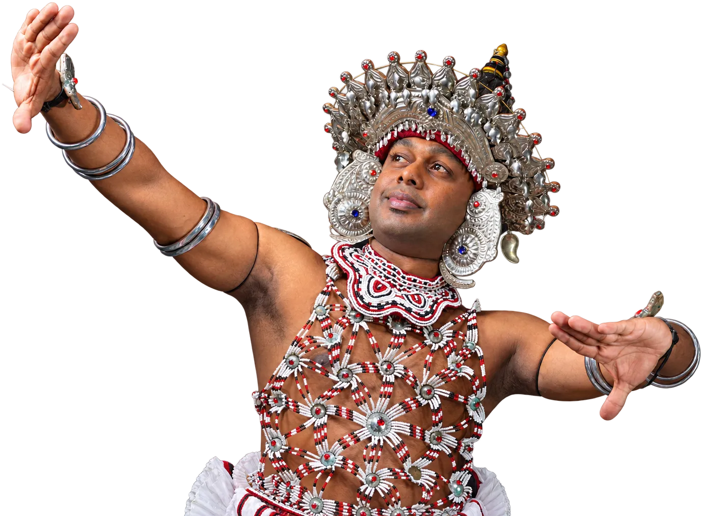 A Kandyan dancer in the silver headdress and beaded ves costume, arms spread wide