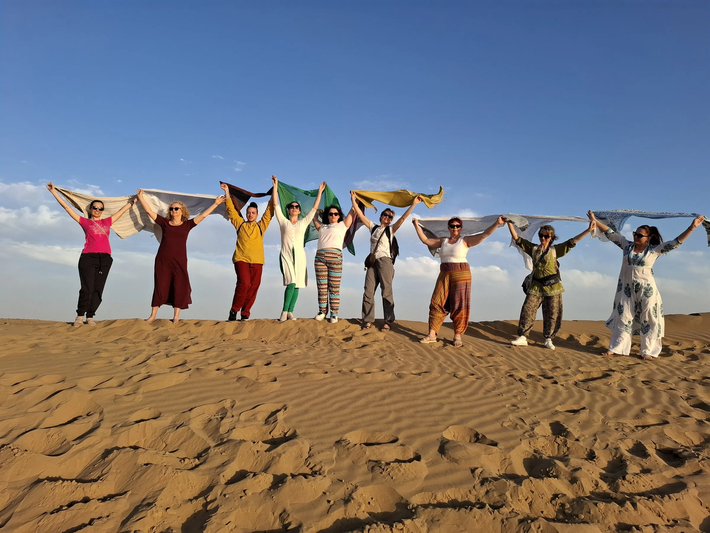 Travellers on the dunes of the Thar, scarves held up in the wind