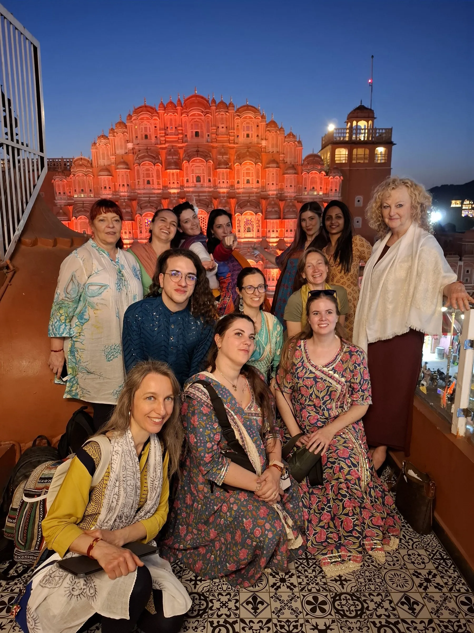 Travellers in Indian dress, the Hawa Mahal lit up behind them
