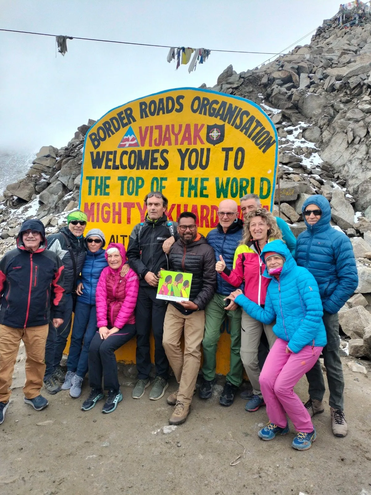 Travellers in down jackets by the Border Roads sign on Khardung La