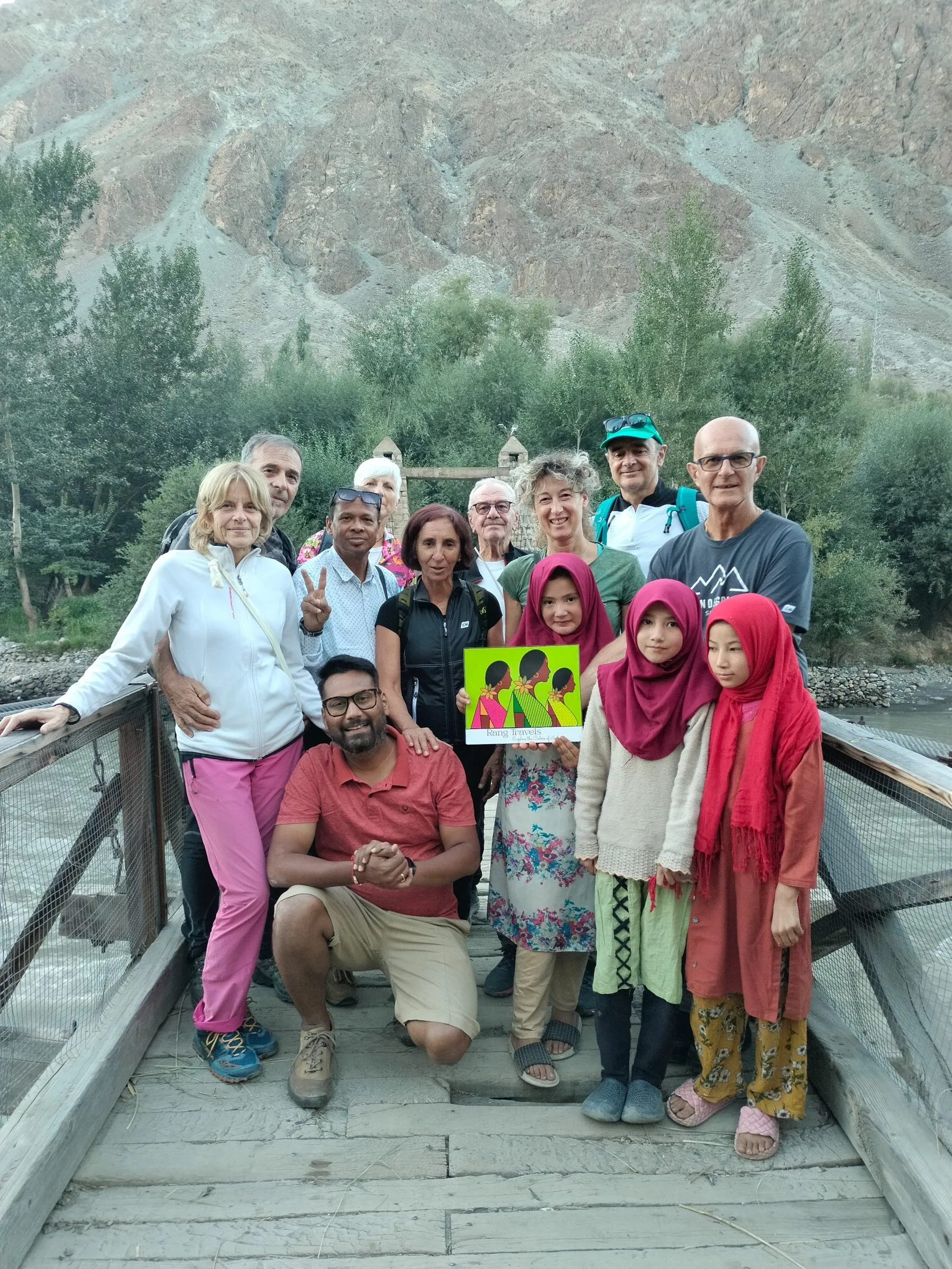 Travellers with the team on a wooden bridge in a mountain valley