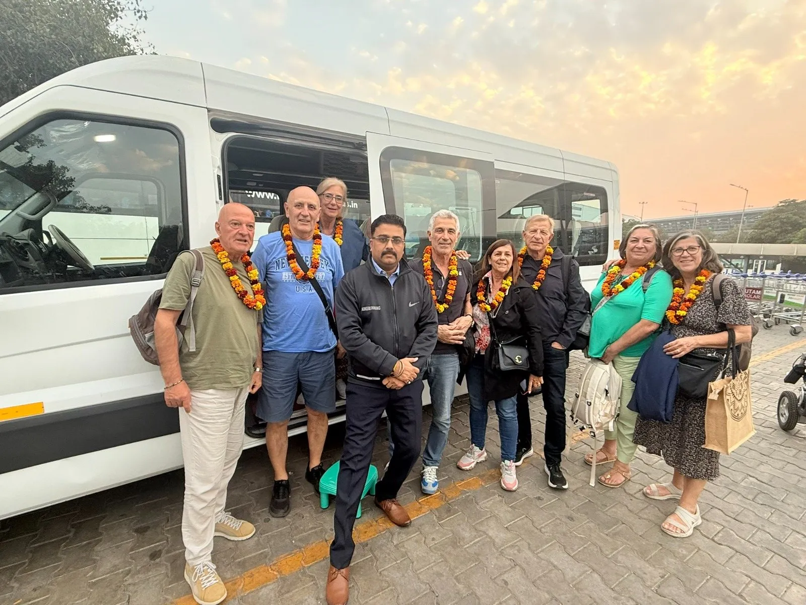Travellers in marigold garlands beside their coach