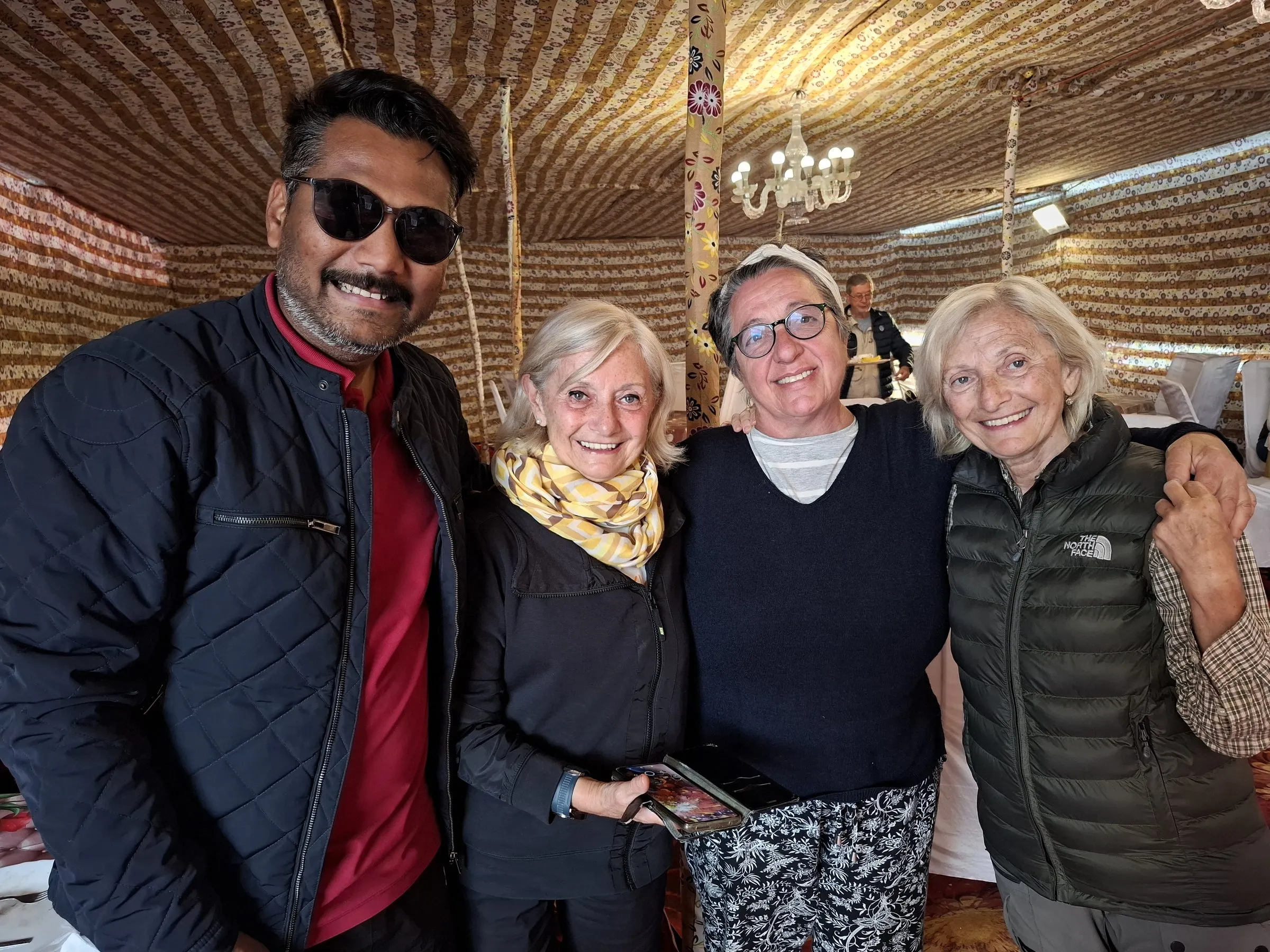 Three travellers with a member of the team in a decorated tent