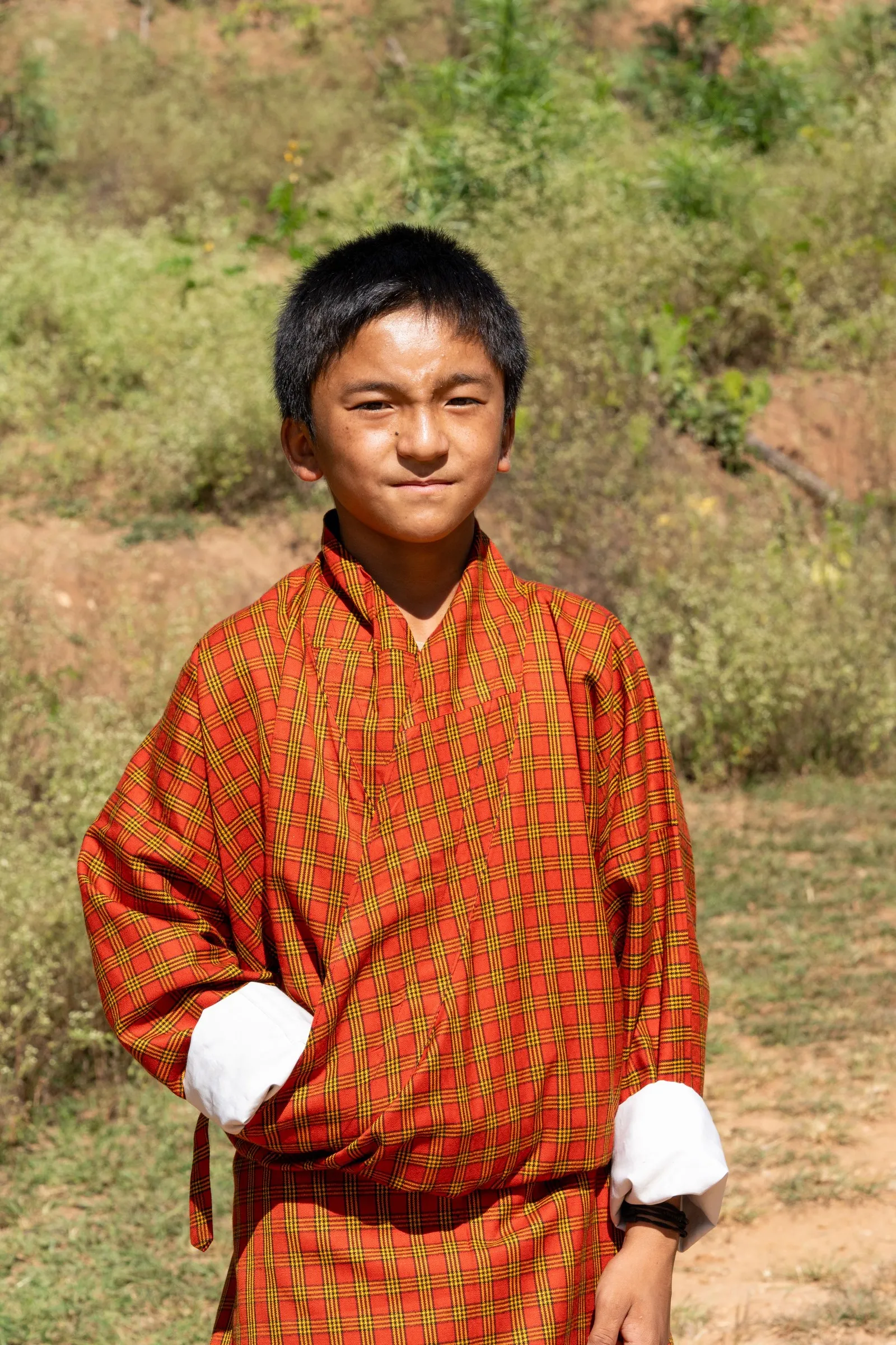 A boy in an orange gho, the traditional dress of Bhutan