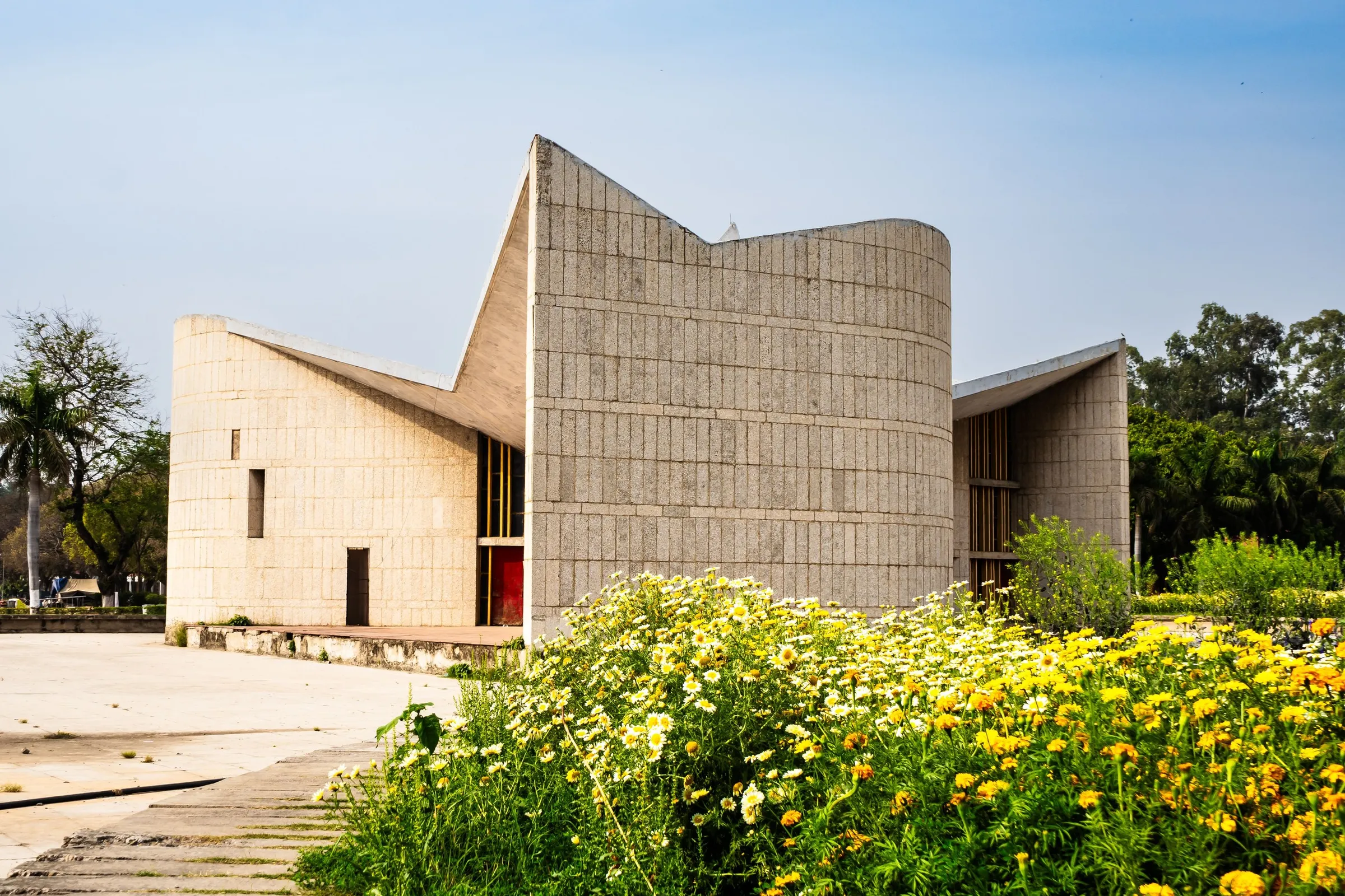 A modernist concrete building in Chandigarh behind a bed of marigolds