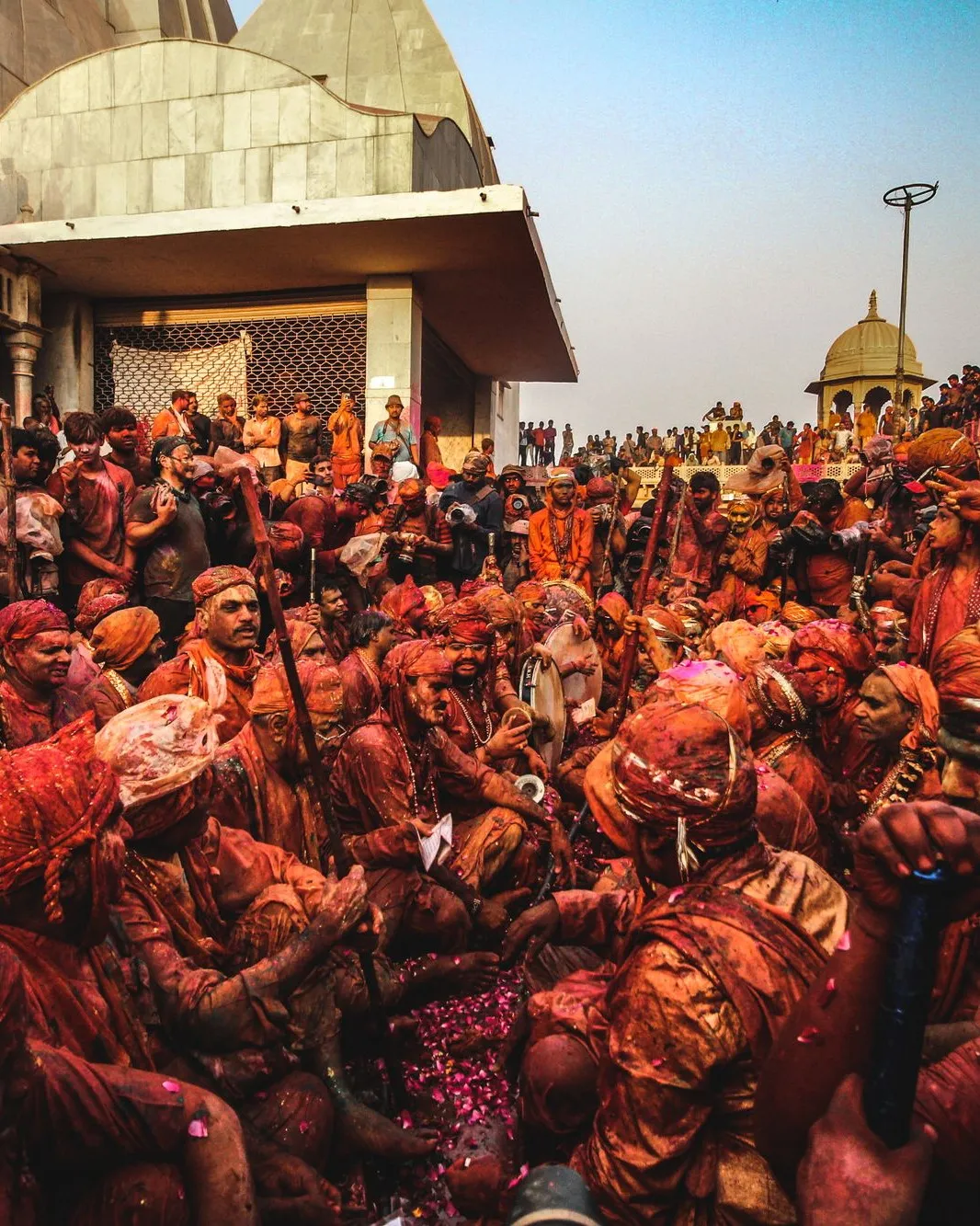 The crowd under a Barsana temple, red with colour
