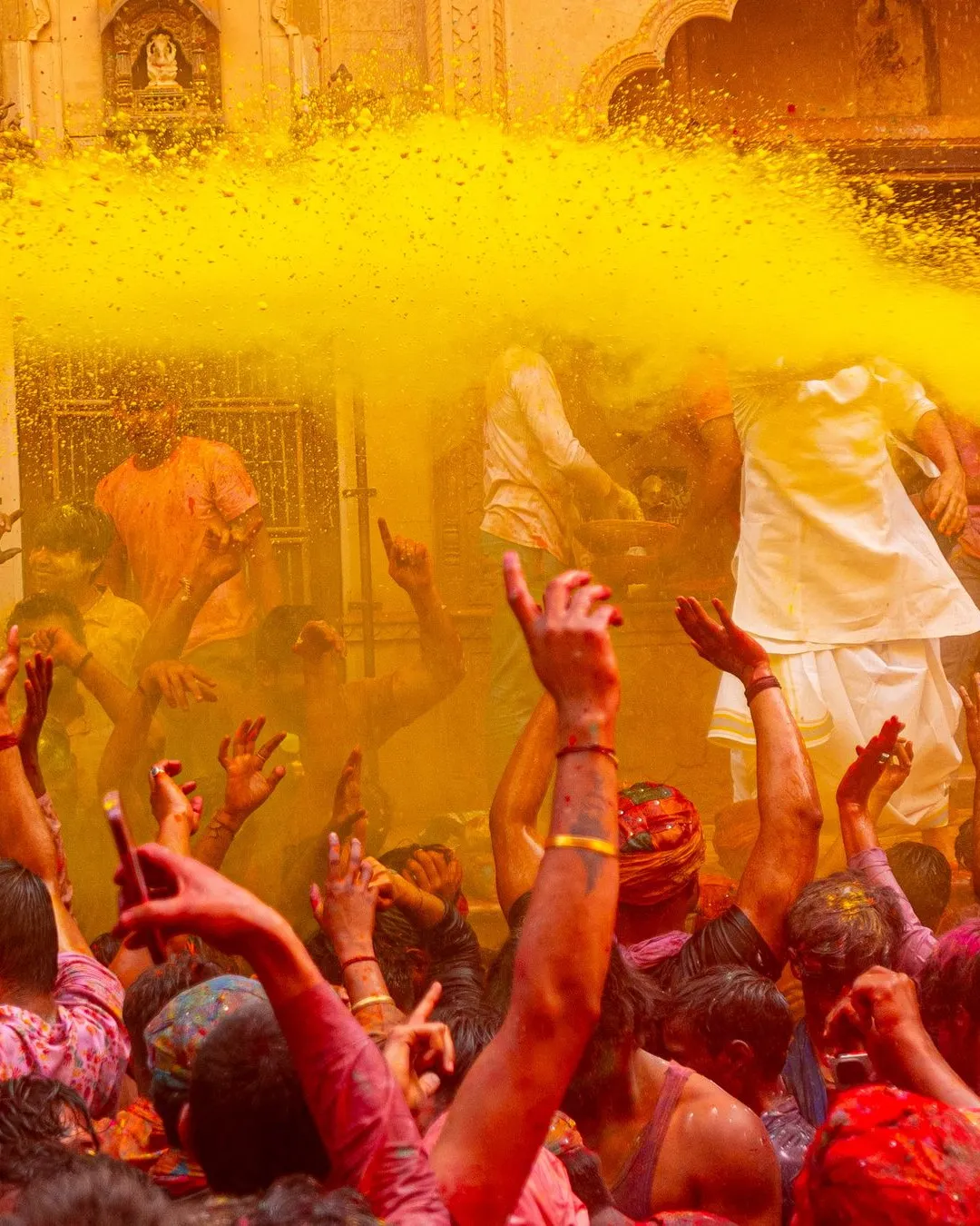 Yellow gulal thrown over the crowd outside a temple