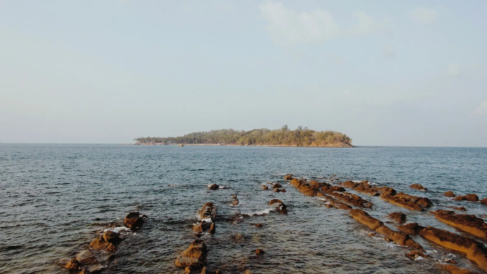 The rocky shore at Port Blair, an island offshore in the morning light