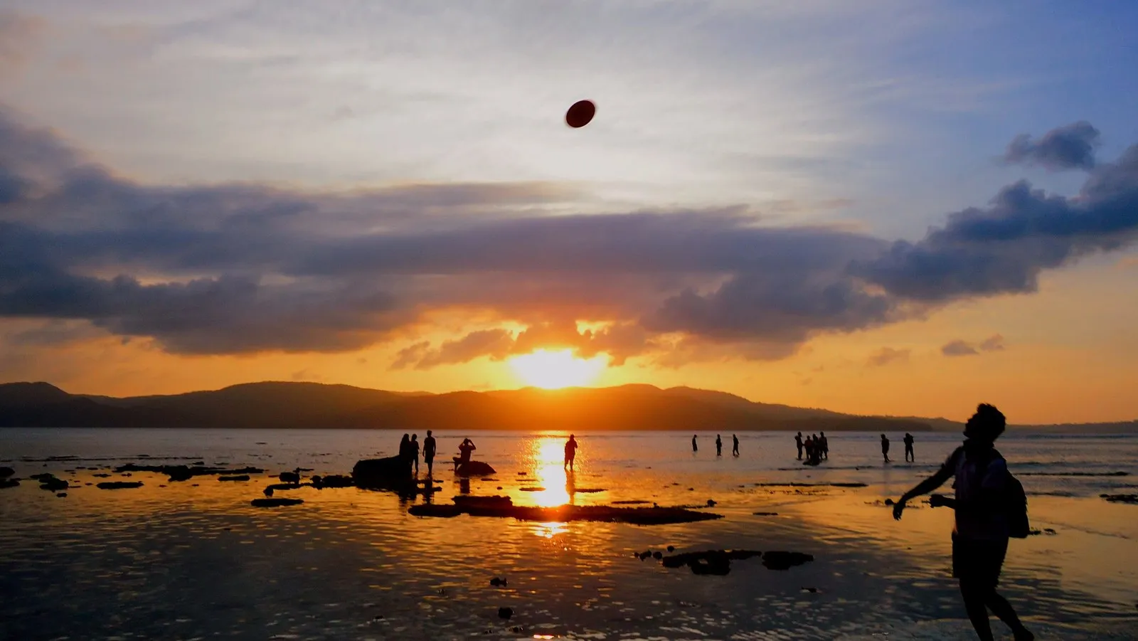 People on the shore at low tide at sunset, Port Blair