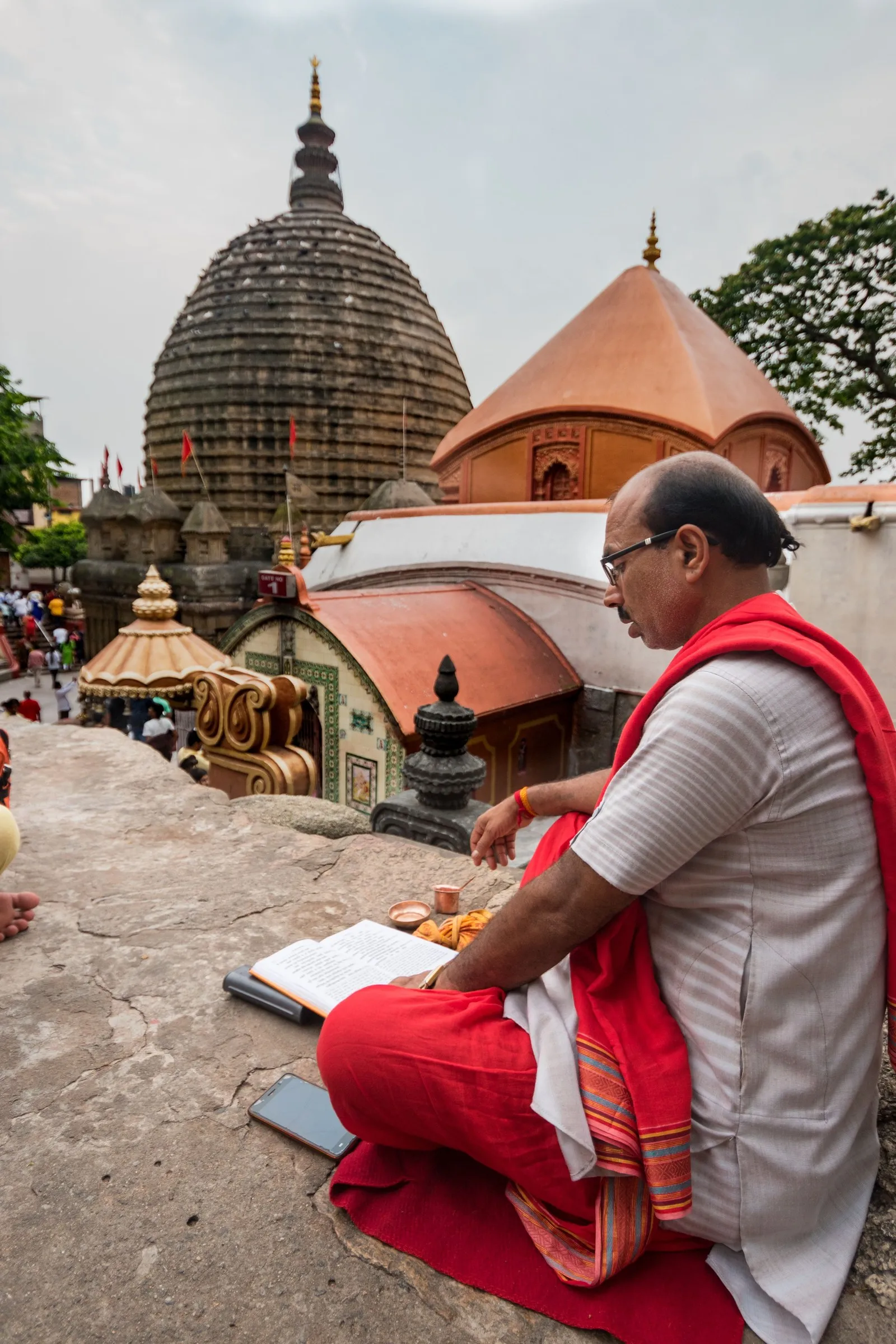 A priest reading scripture on the rock below the beehive spire of the Kamakhya temple, Guwahati