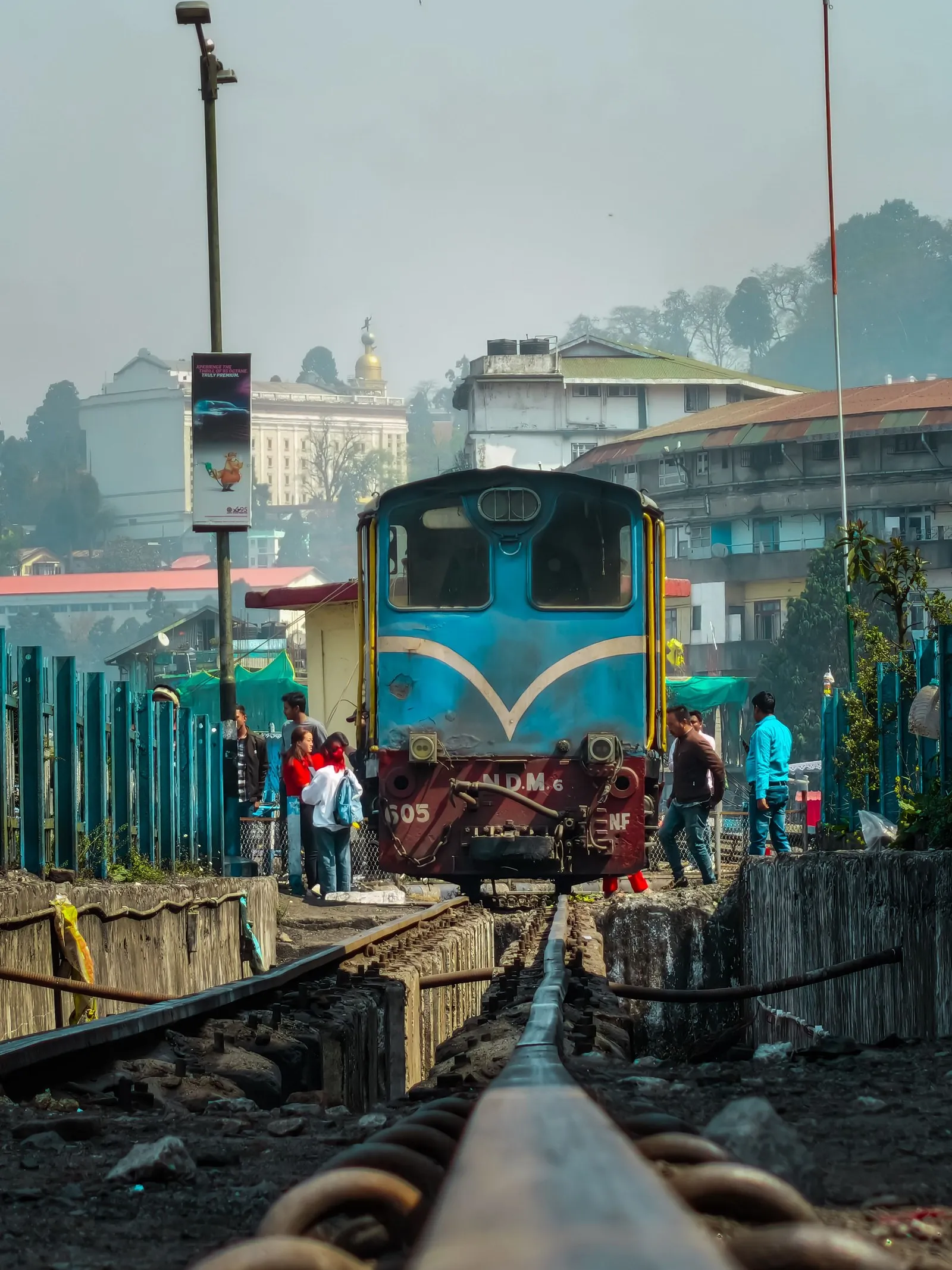 A blue diesel engine of the toy train at Darjeeling station, passengers crossing the line