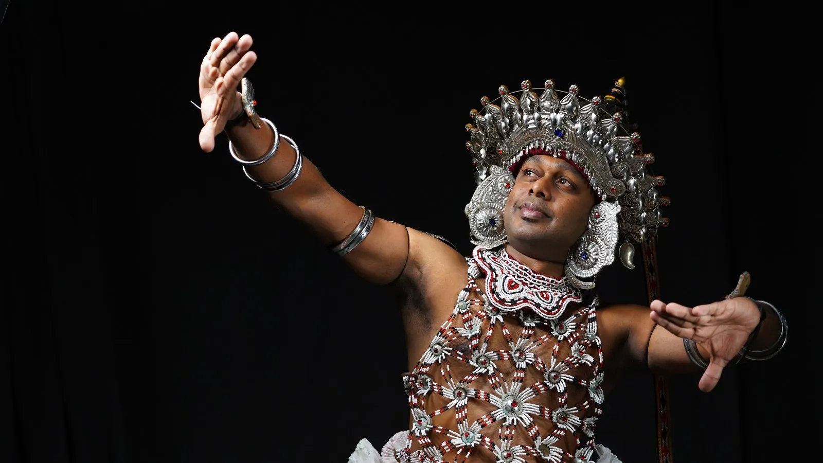A Kandyan dancer in the silver headdress and beaded ves costume
