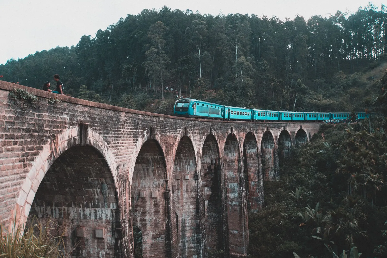 A blue train crossing the Nine Arch Bridge near Ella