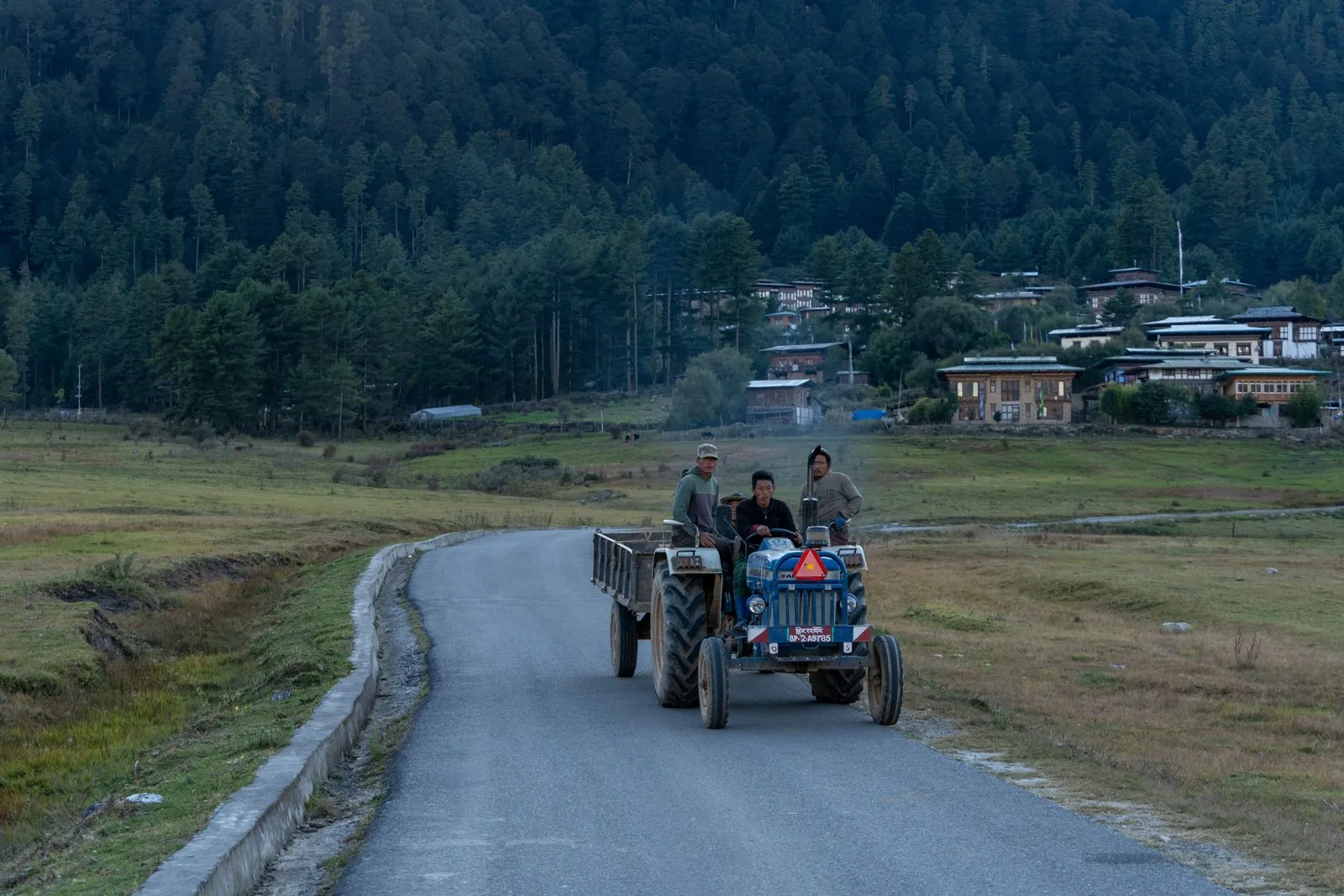 Farmers riding a tractor along a valley road in Bhutan