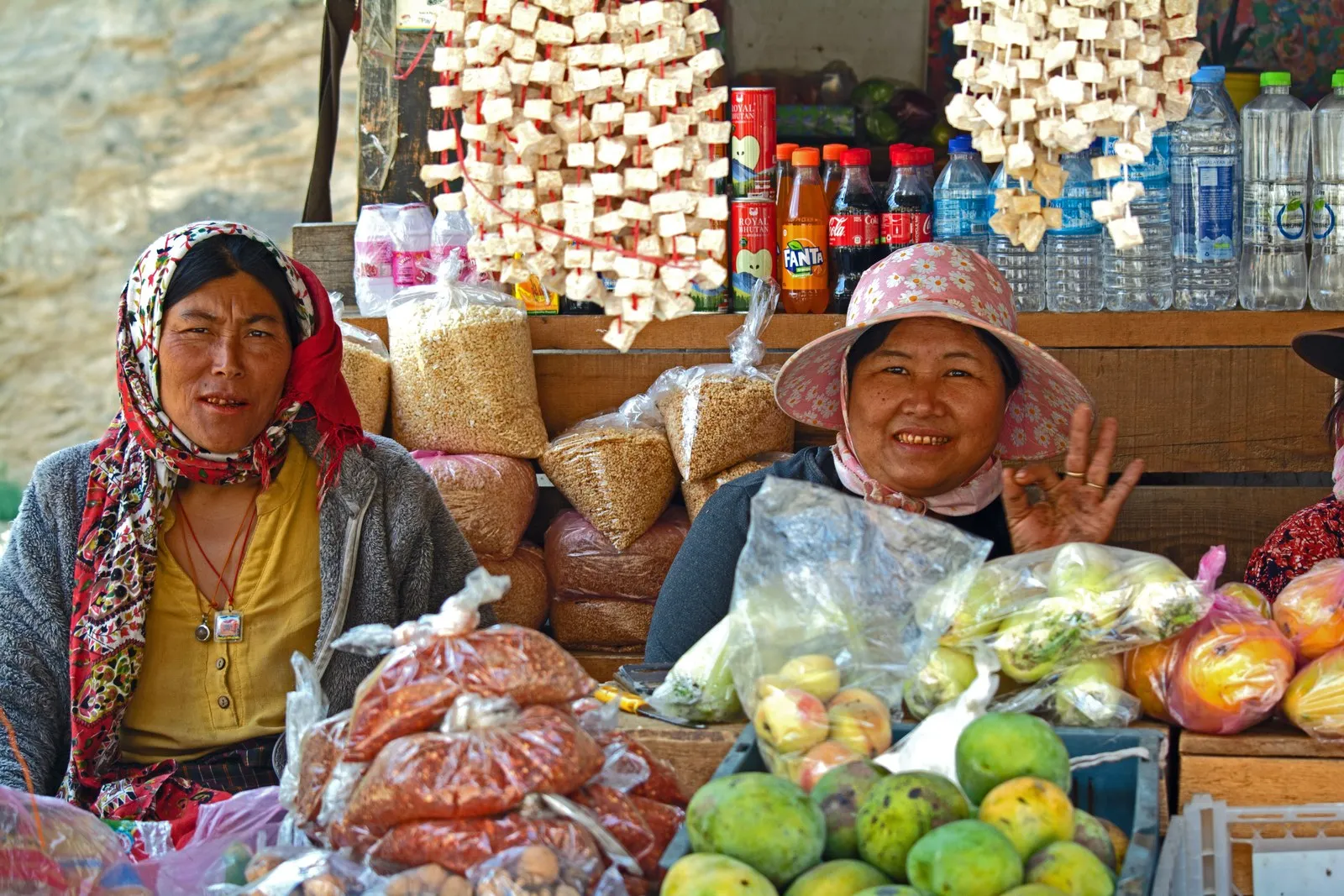 Two women at their market stall in Thimphu, strings of dried cheese overhead