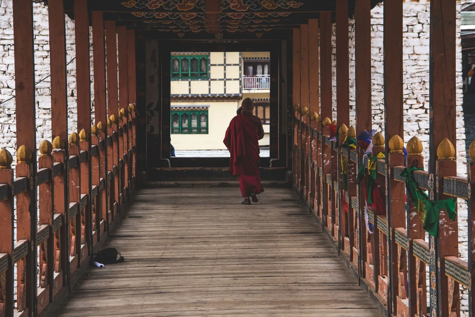 A monk crossing a covered wooden bridge in Thimphu