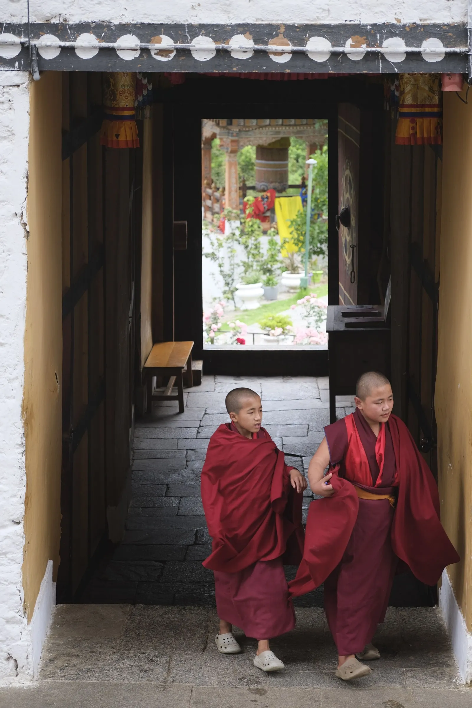 Two novice monks walking through a monastery passage, Bhutan