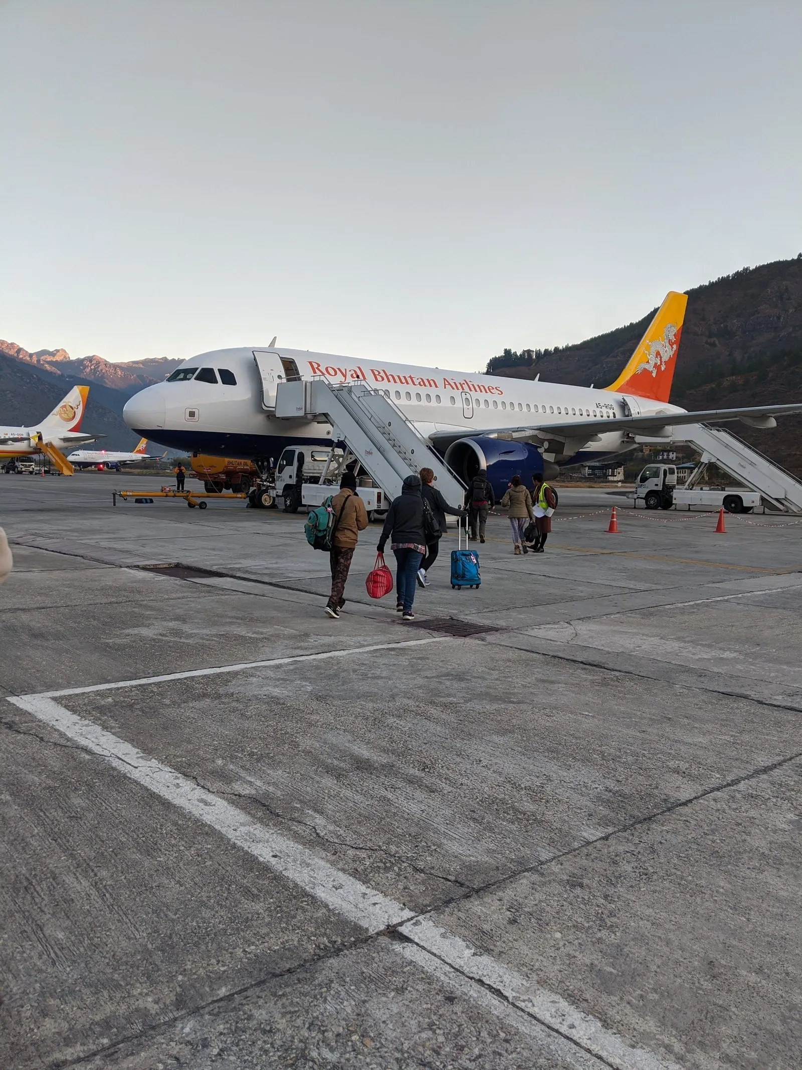 Passengers crossing the apron to a Druk Air plane at Paro airport, the hills behind