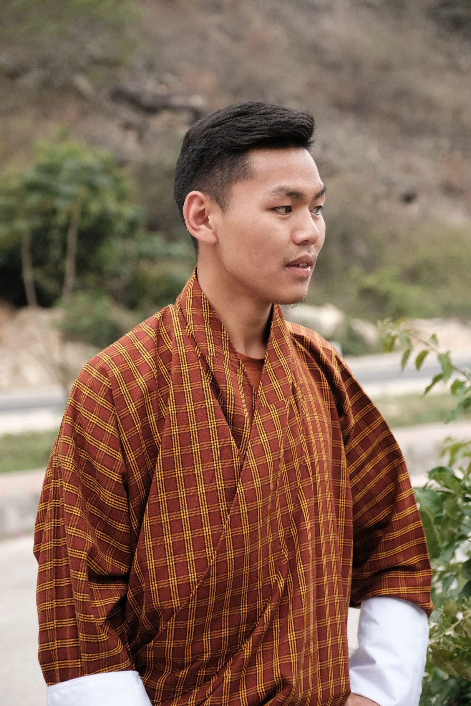 A young man in a checked gho near Thimphu