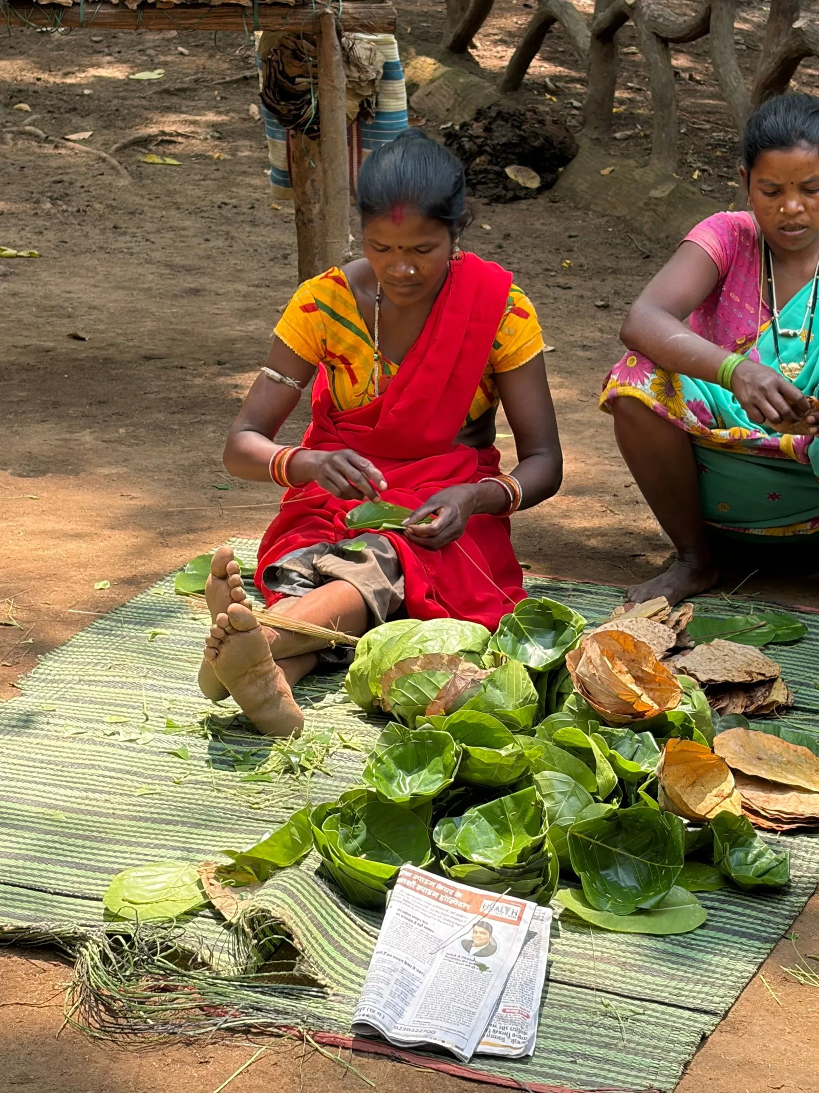 Two women stitching sal leaves into plates in Chhattisgarh