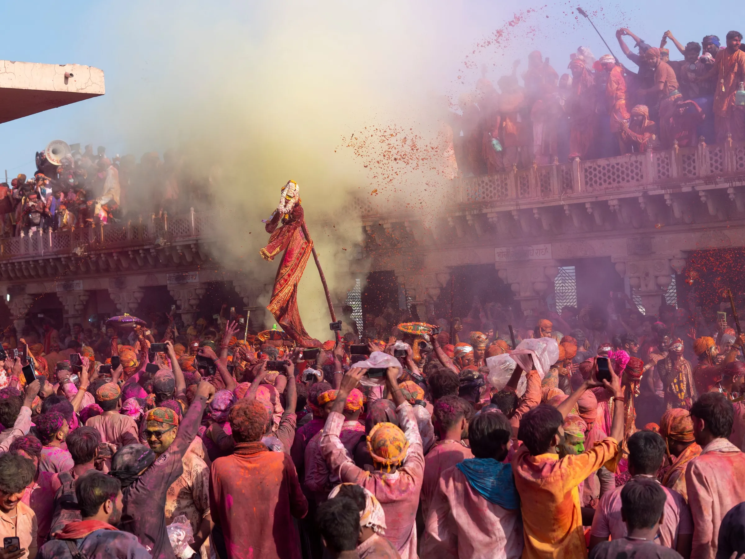 The crowd at Barsana under a cloud of colour, the temple above them