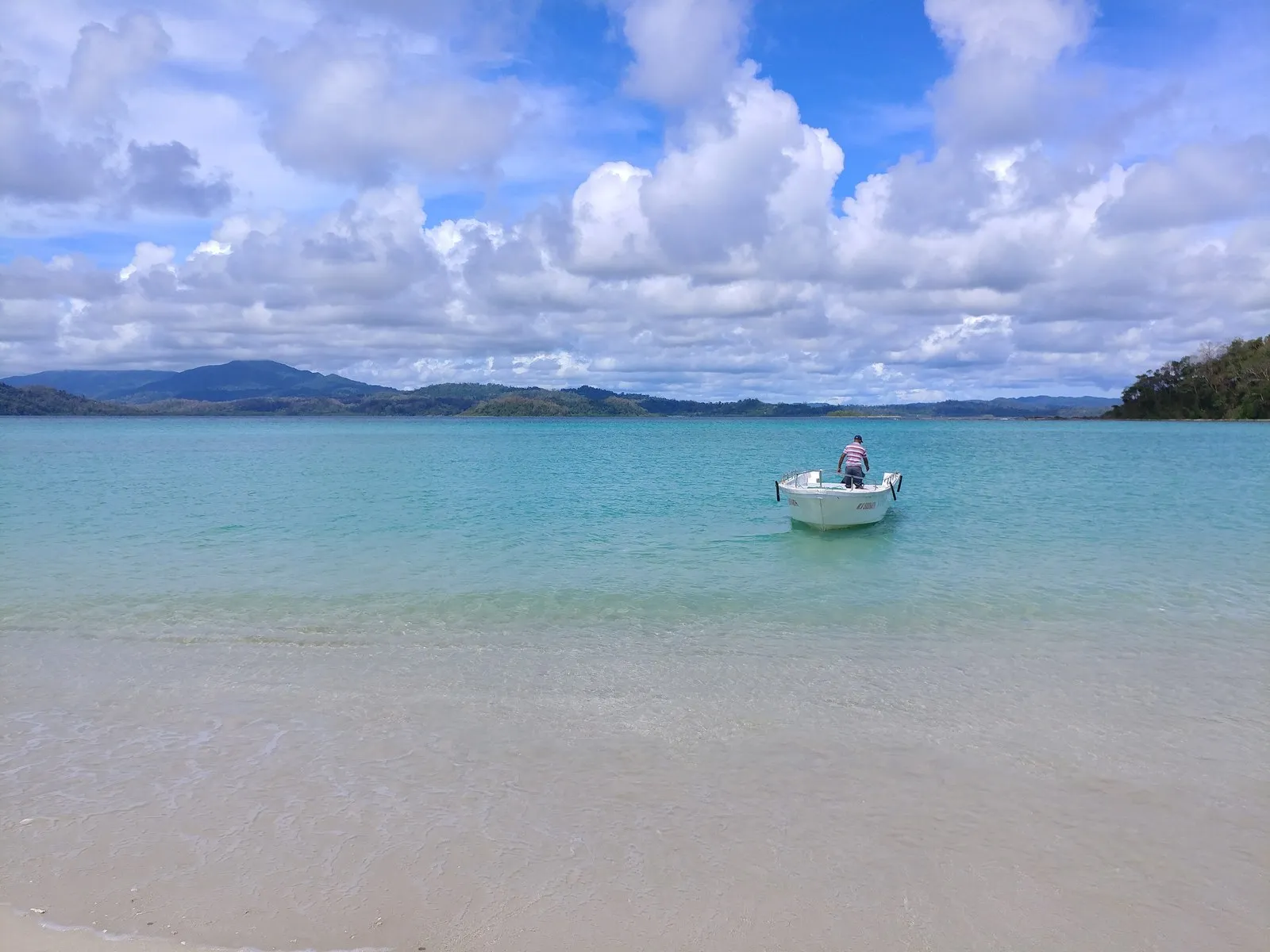 A boat on clear water off the white sand of Ross and Smith Islands, near Diglipur