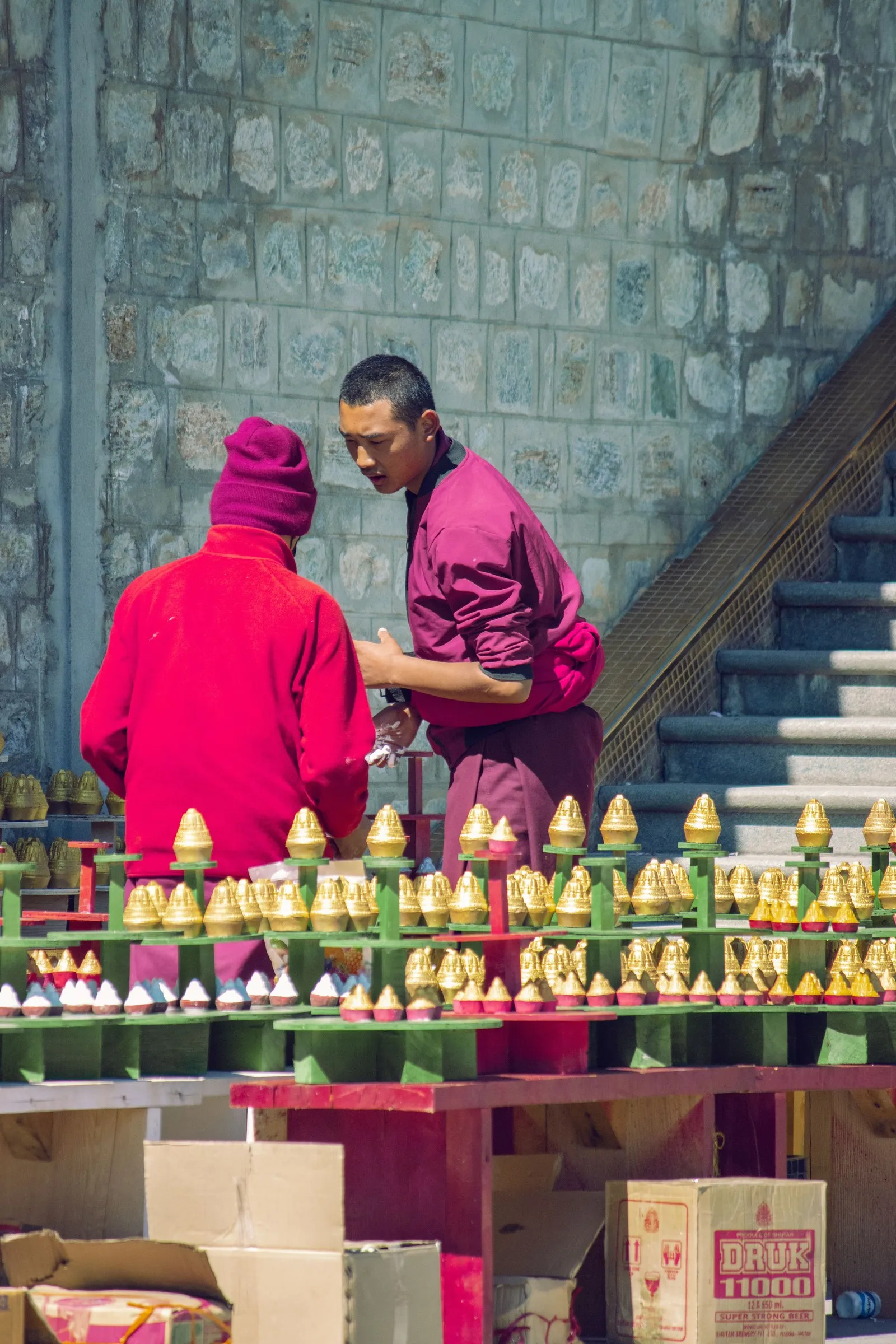 Two monks setting out butter-lamp offerings in Thimphu
