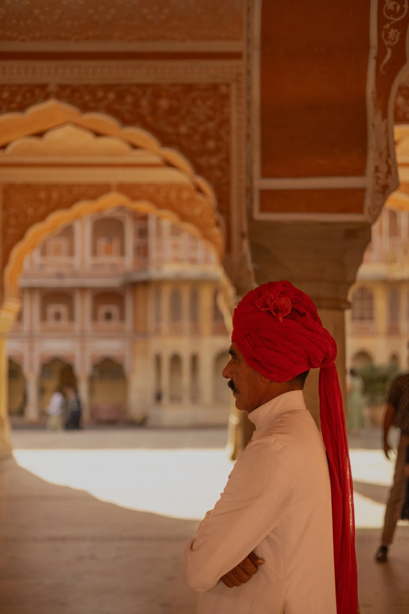 A palace attendant in a red turban under the arches of the City Palace, Jaipur