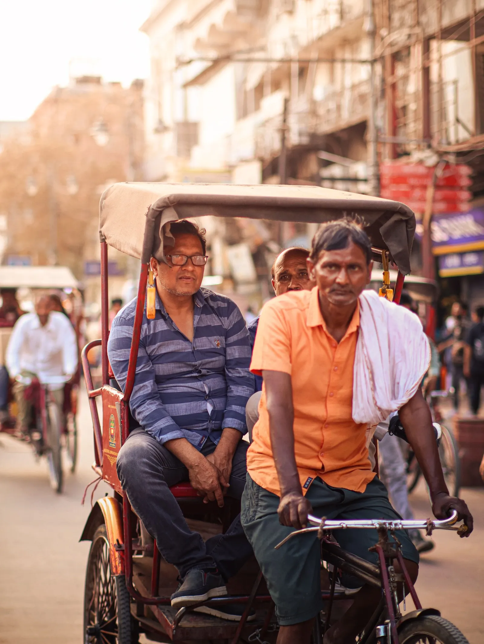 A cycle rickshaw and its passengers in a Delhi street