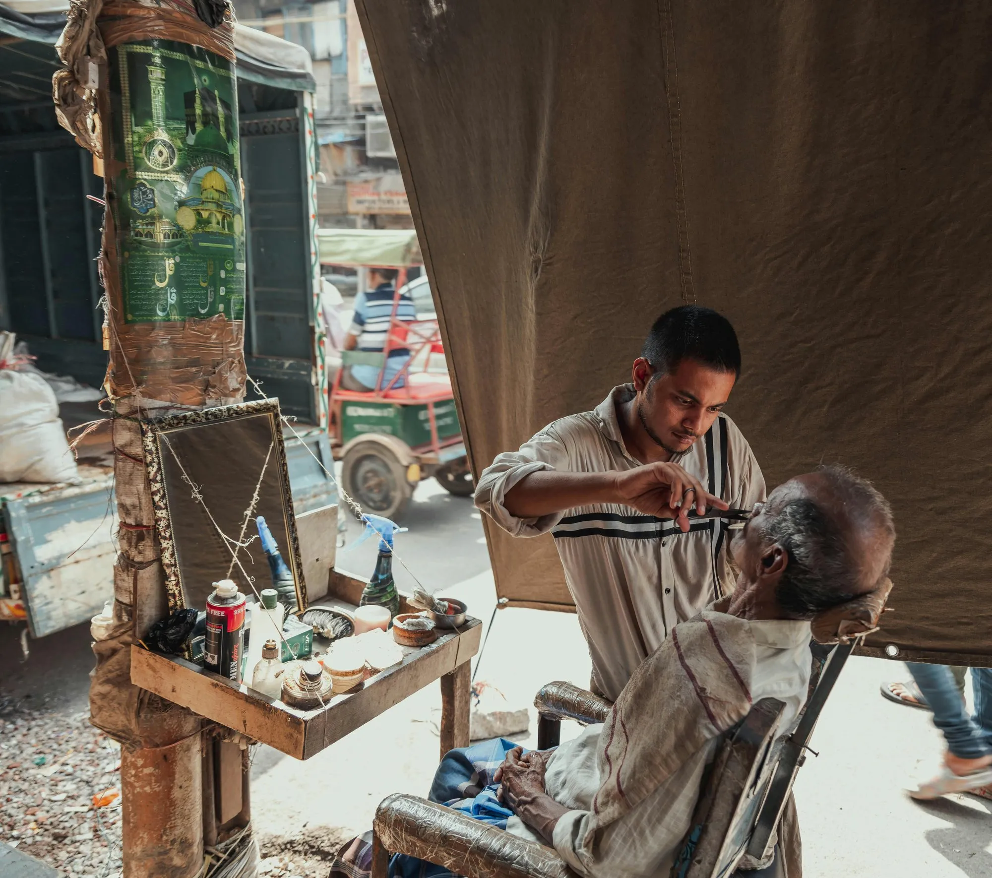 A street barber shaving a customer in Old Delhi