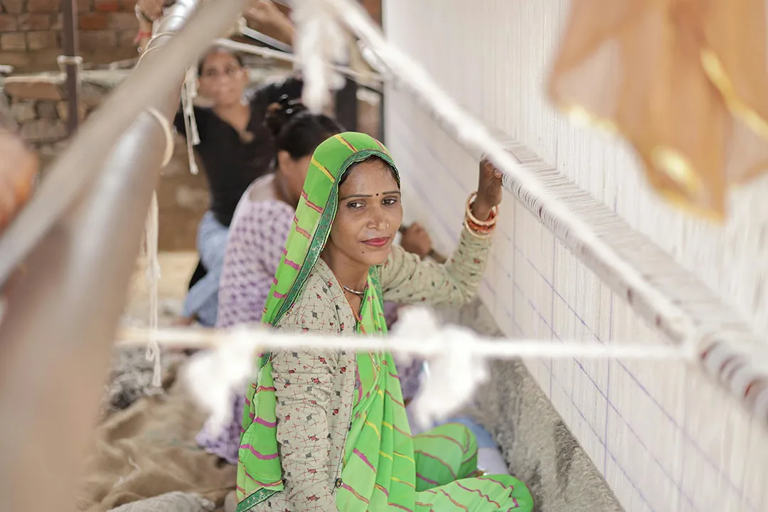A woman at work behind lines of cotton thread