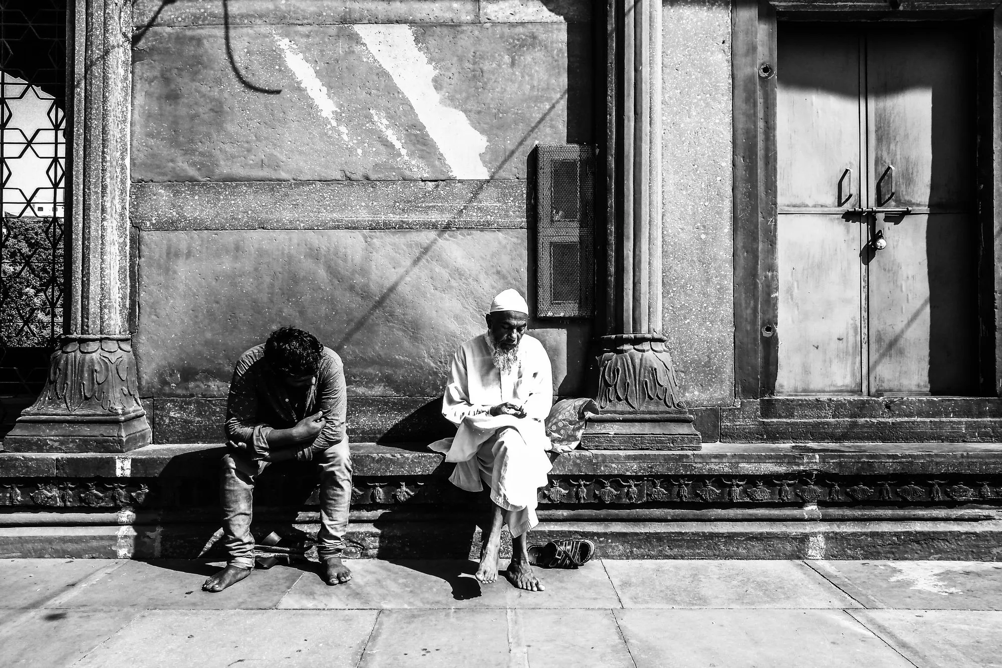 Two men resting on a temple step, in black and white