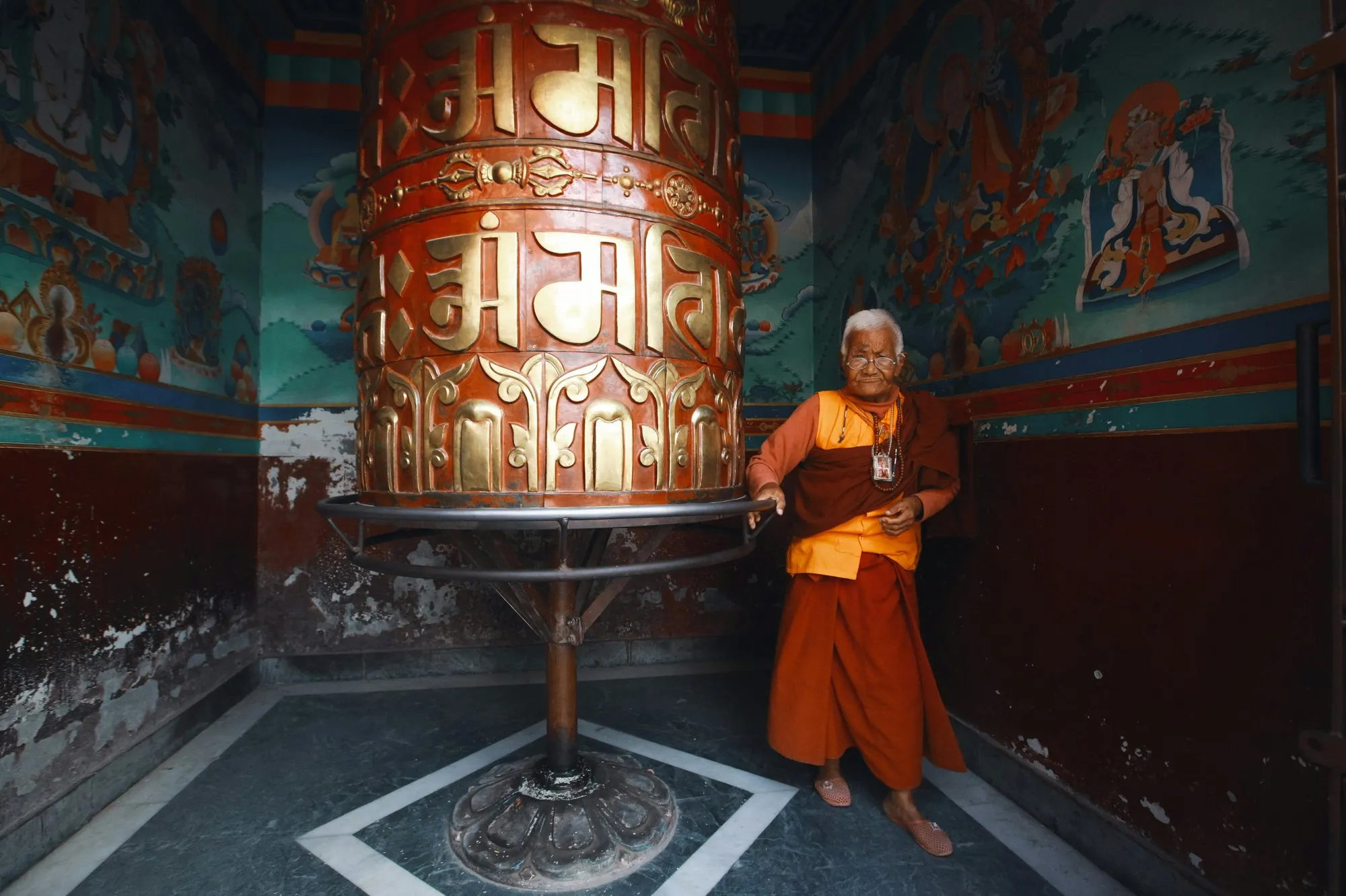 A nun beside a great copper prayer wheel