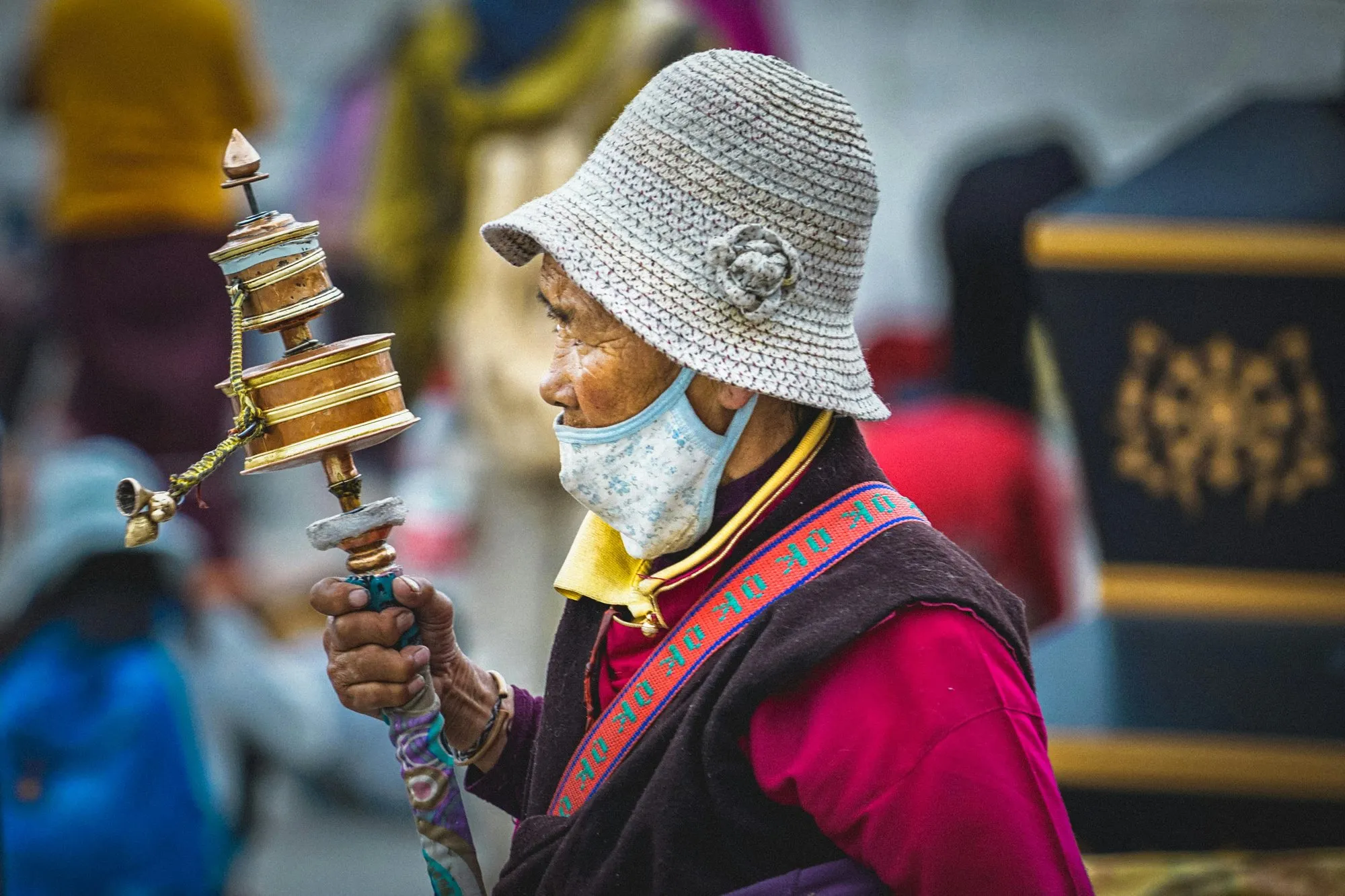 A woman turning a hand prayer wheel