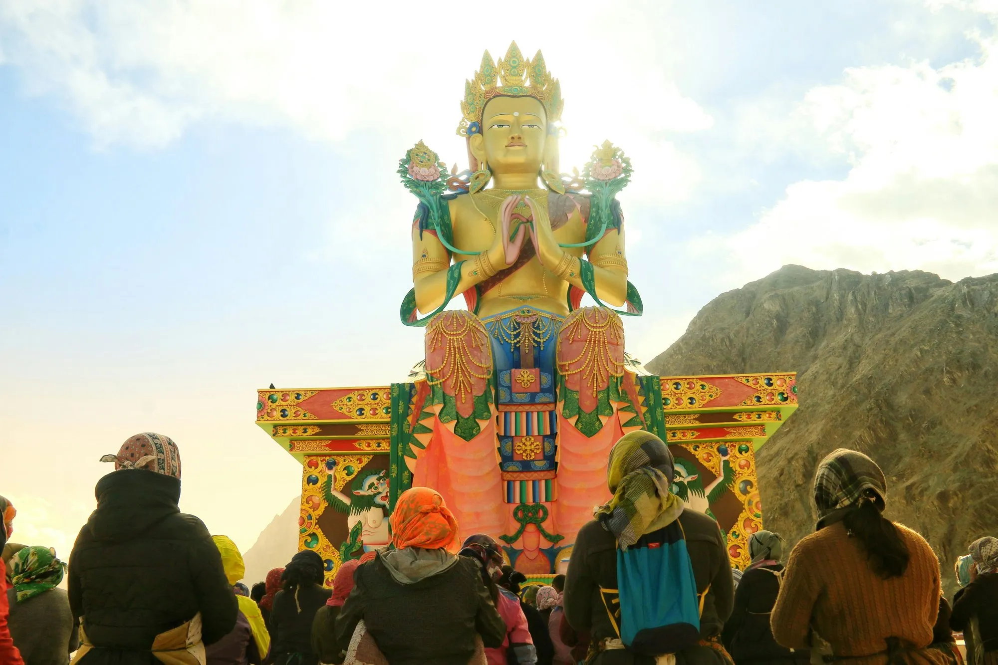 A giant golden Buddha above a crowd of pilgrims