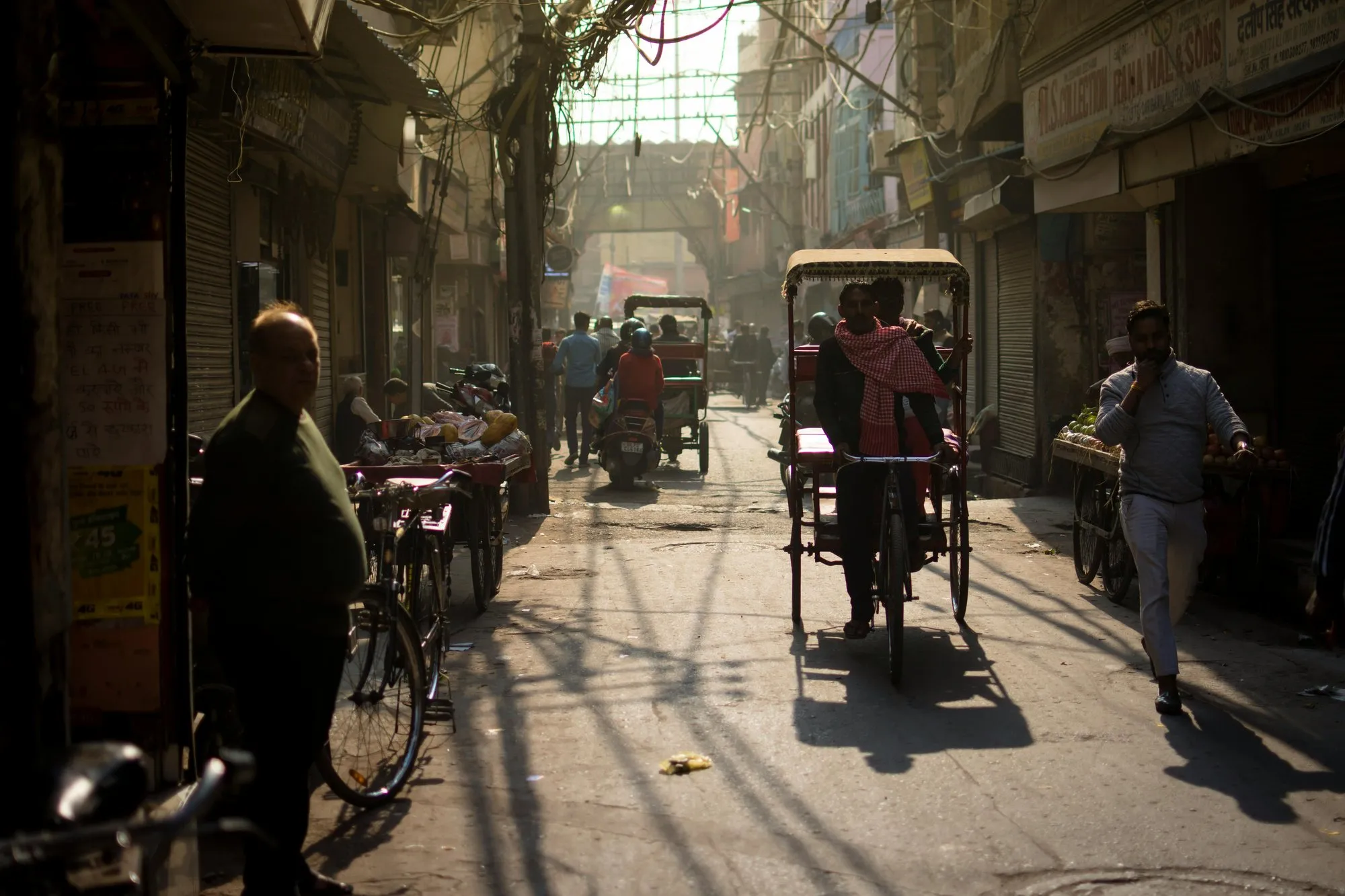 A cycle rickshaw in a sunlit Old Delhi lane
