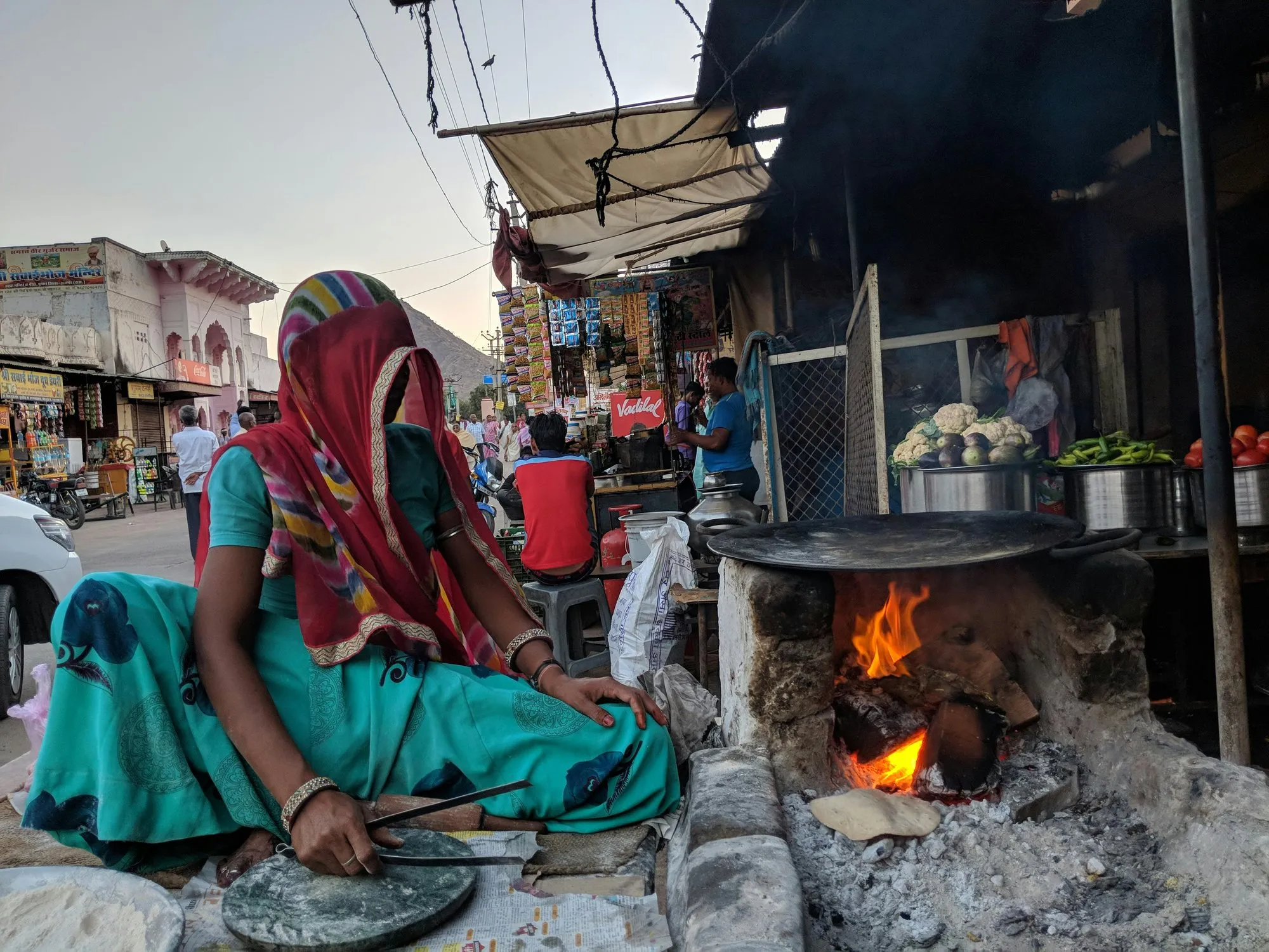 A woman cooking over a wood fire at a street stall