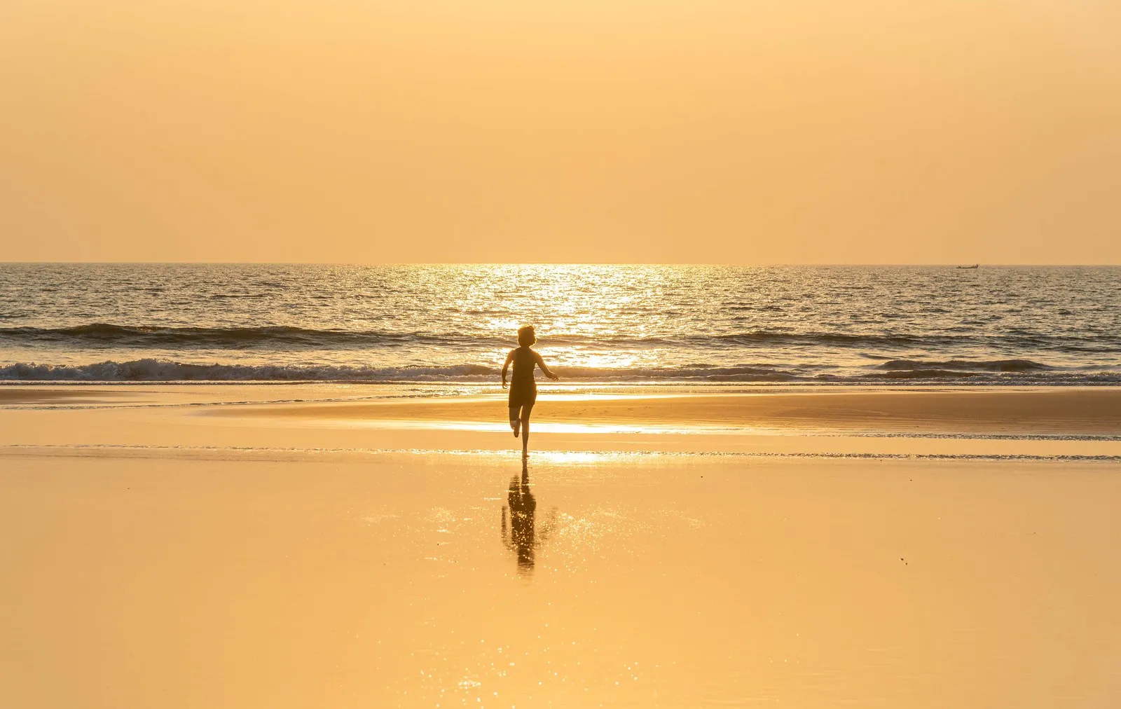 A child running along a Goa beach at sunset