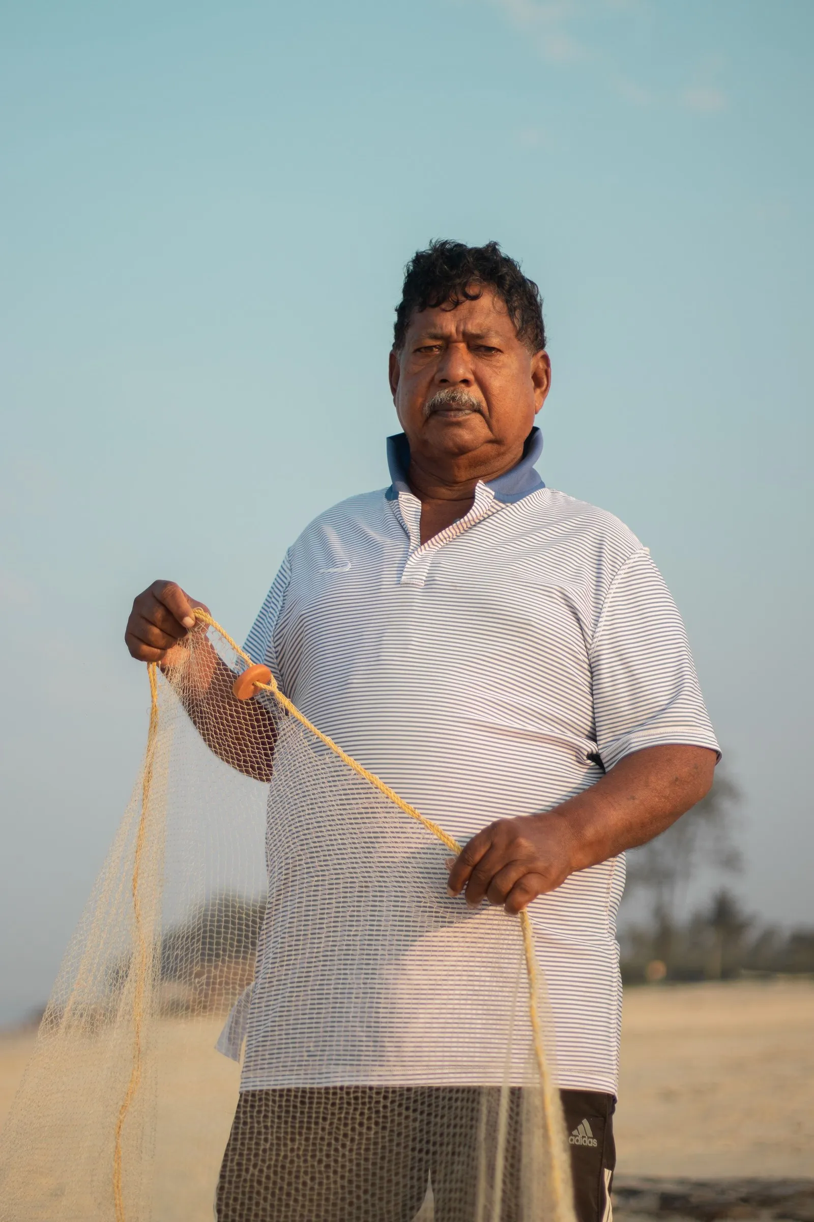 A fisherman holding his net on a beach in Goa