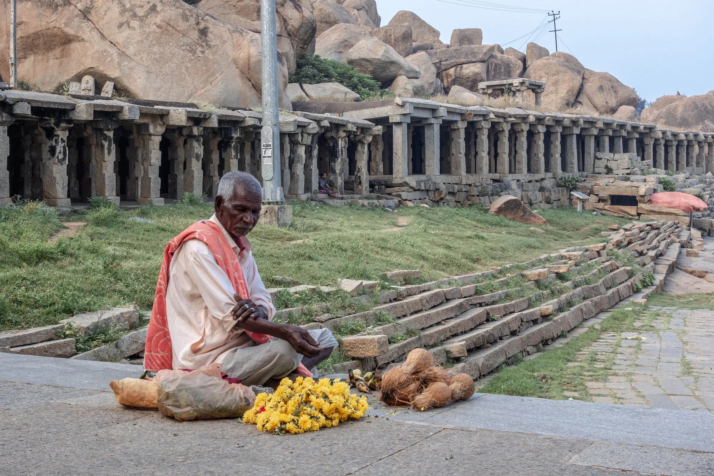 A flower and coconut seller below the old colonnades of the Hampi Bazaar