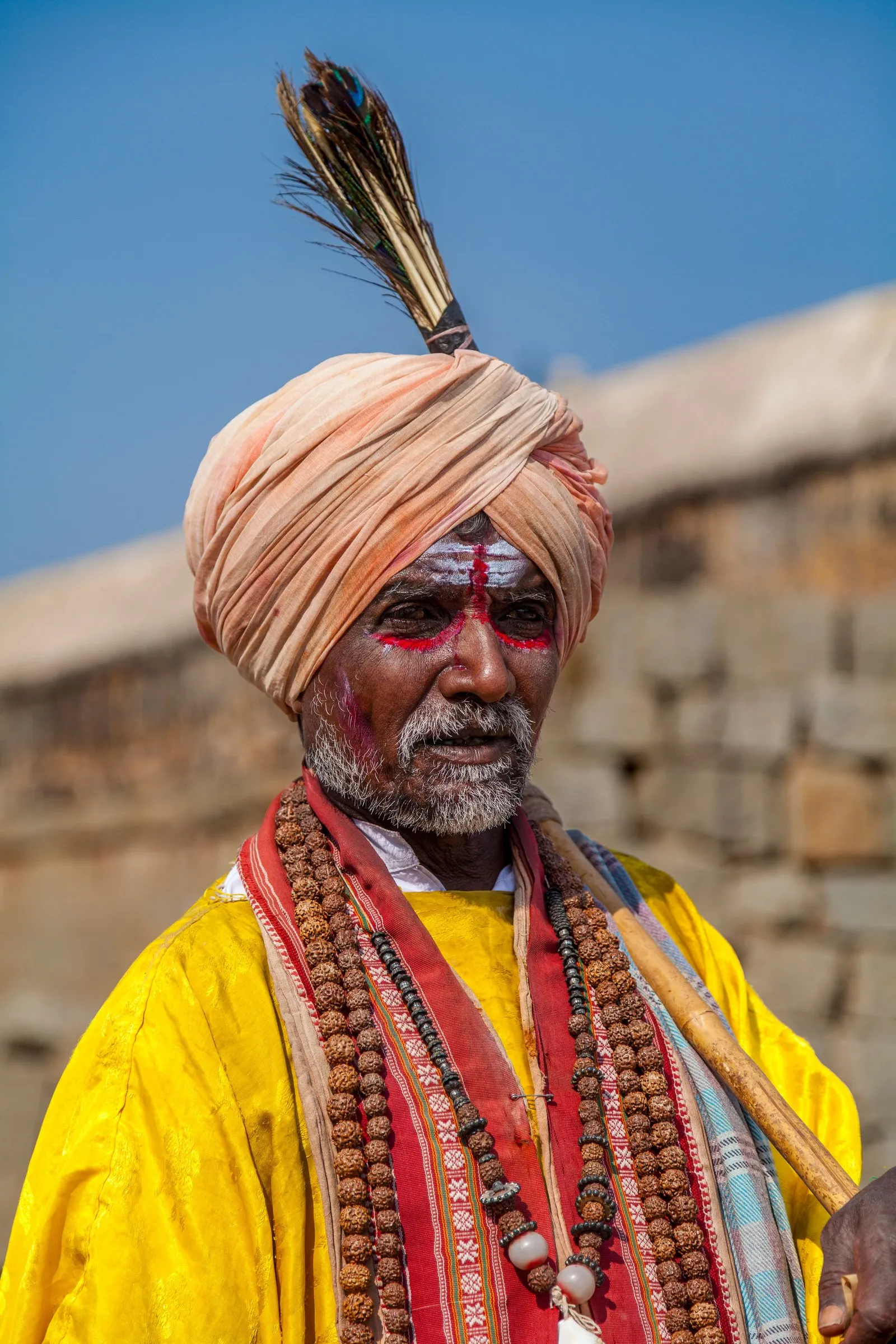A pilgrim in a saffron turban and rudraksha beads at Hampi