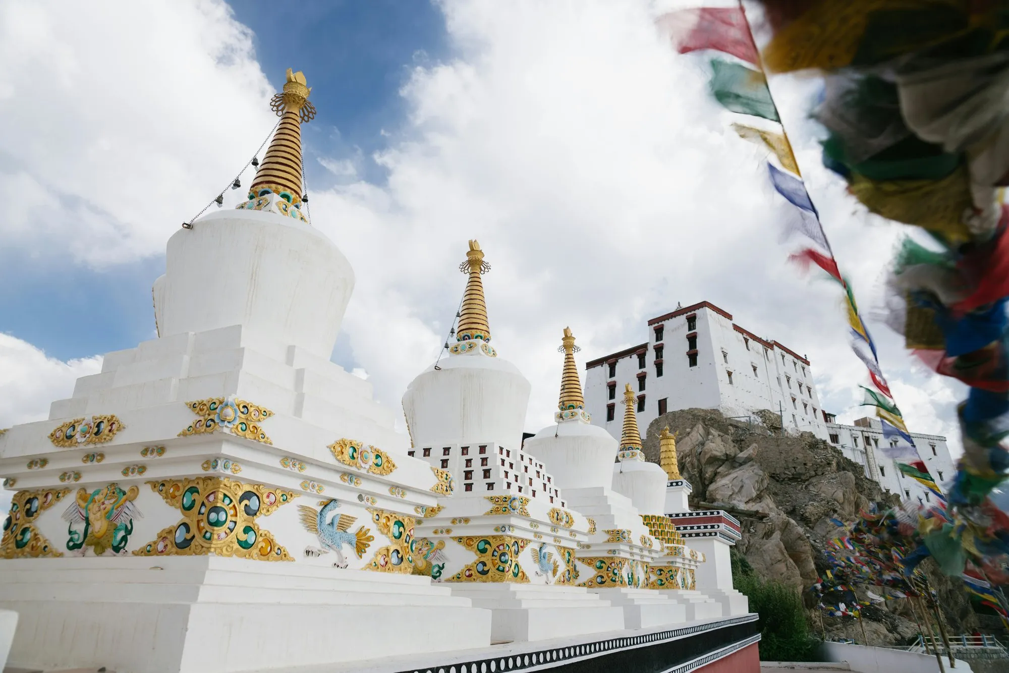 White stupas and prayer flags against the sky
