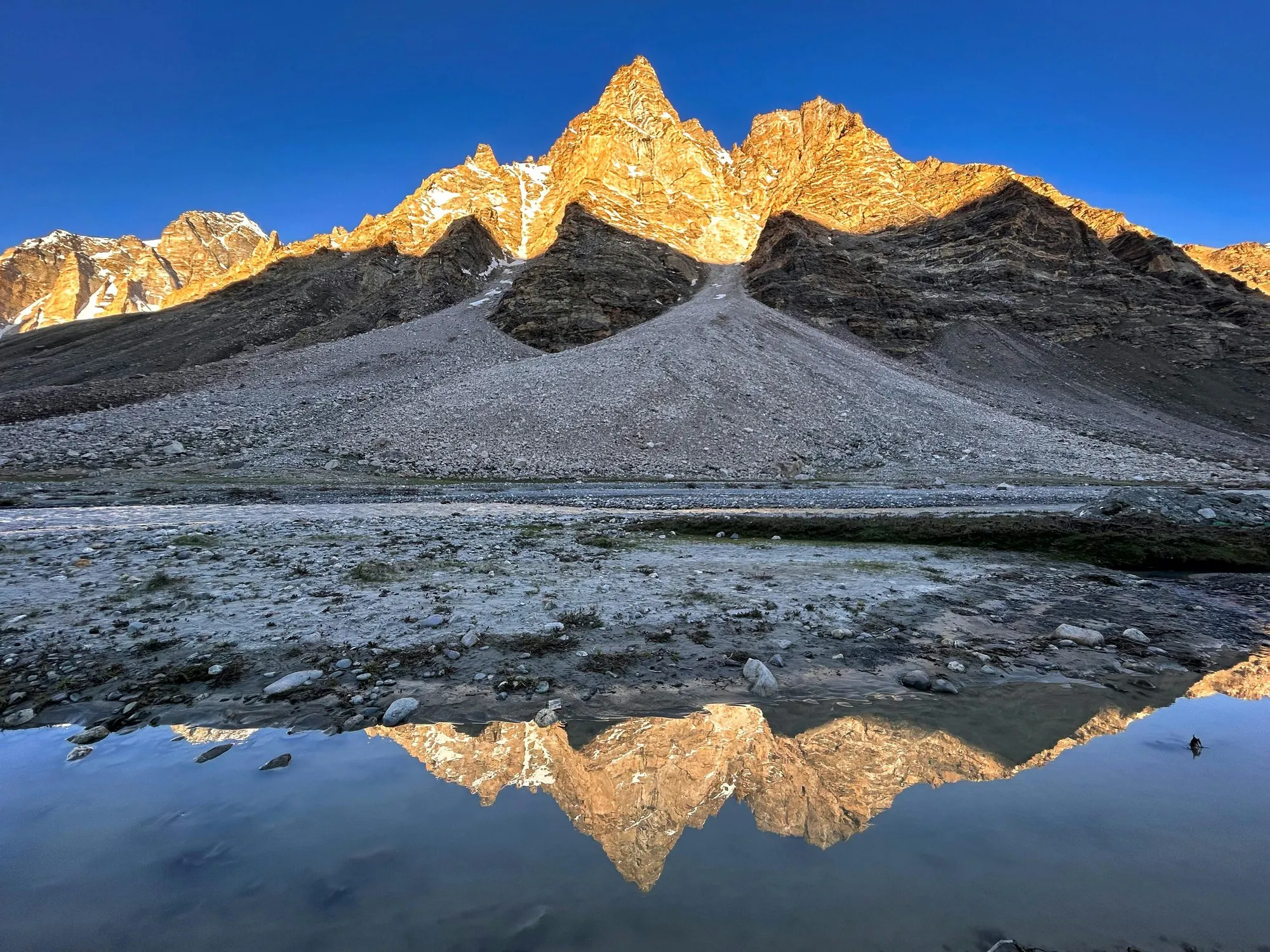A mountain ridge reflected in still water at dawn