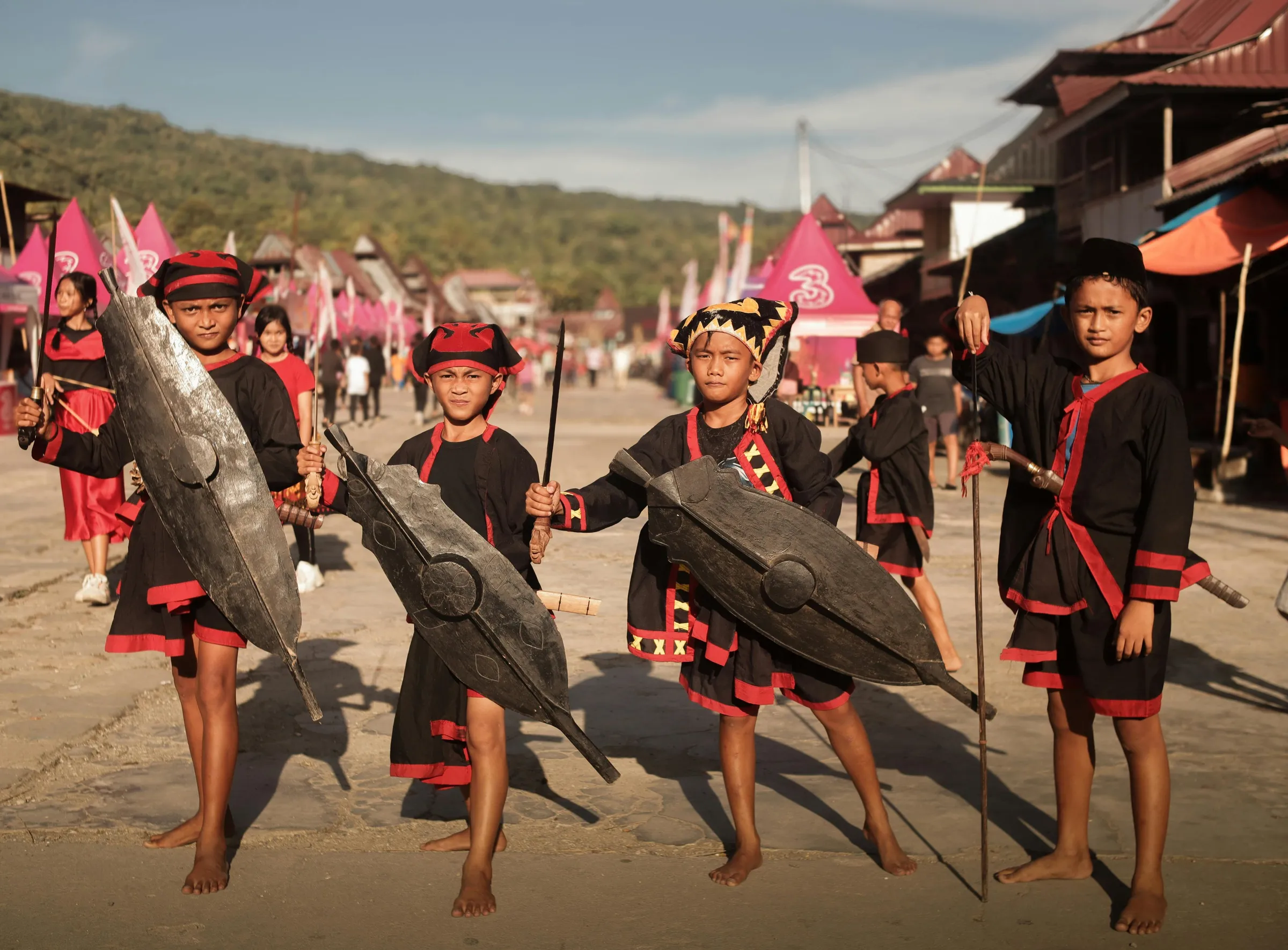 Naga boys in red and black with spears and wooden shields on a festival ground