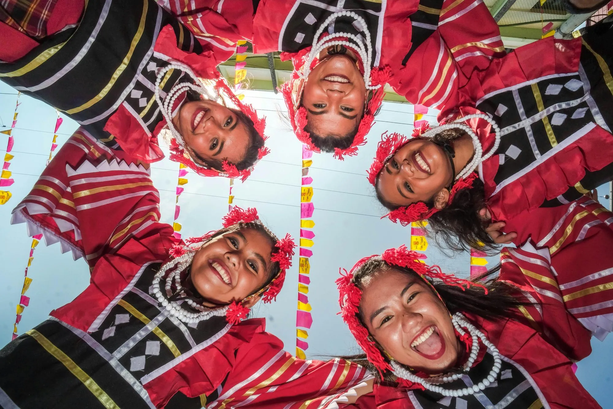 Laughing girls in red Naga shawls, seen from below