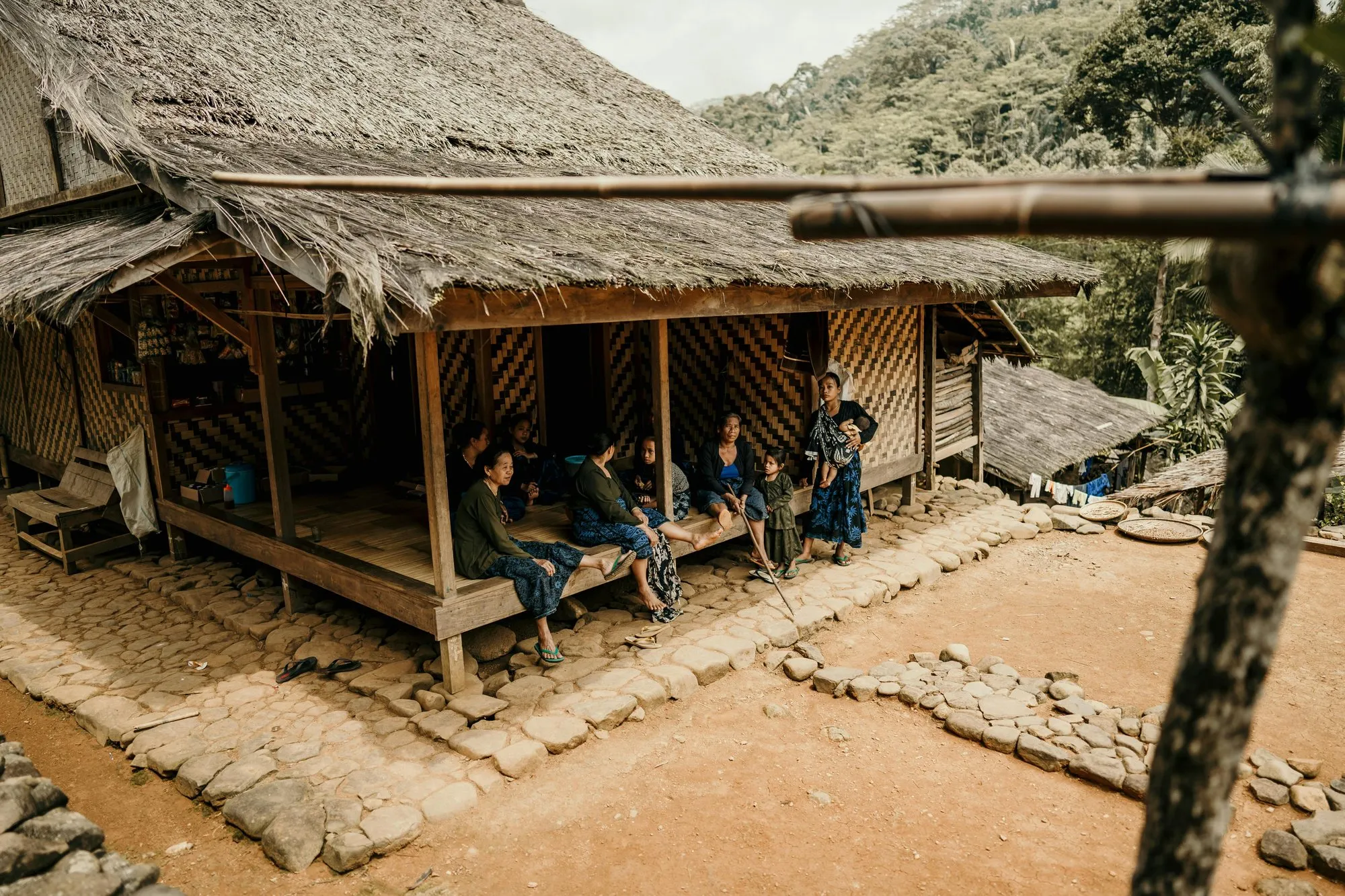 Villagers resting on the porch of a thatched house