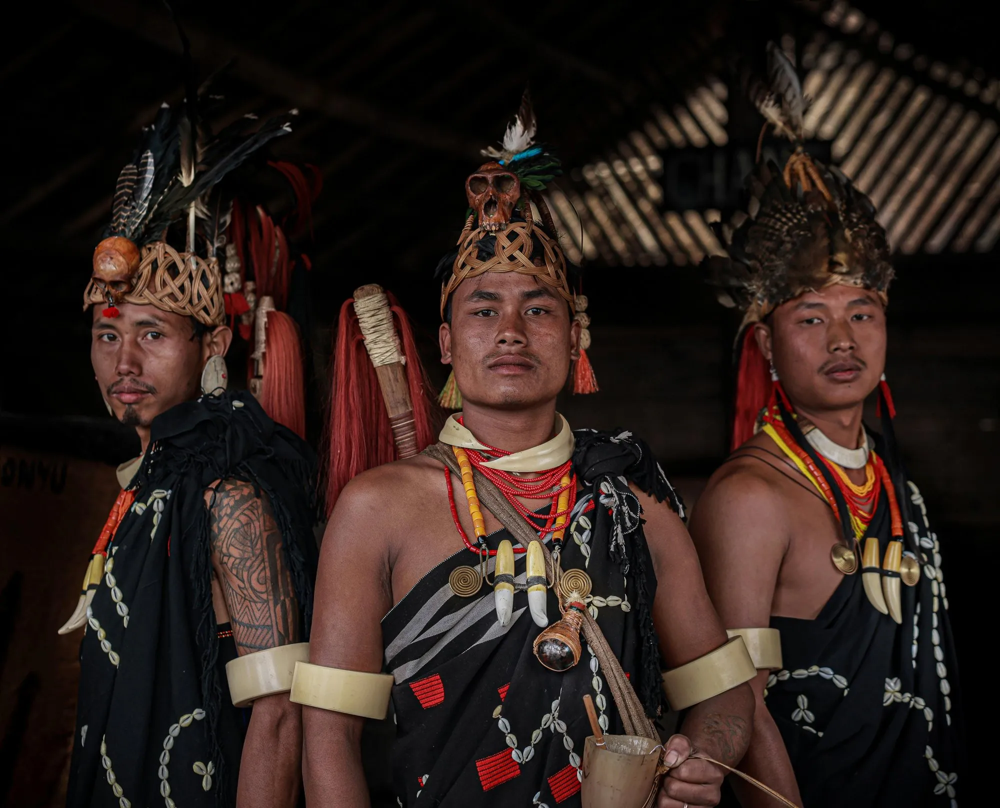 Three Naga men in feathered headdresses and warrior dress