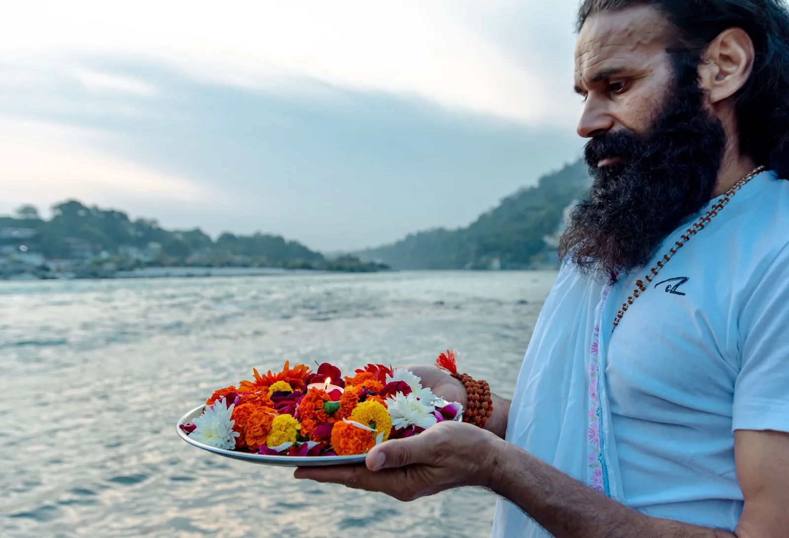 A man holding a plate of marigolds to offer to the Ganga, Rishikesh